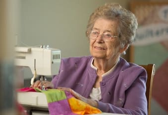 A resident sewing at The Heritage at Fountain Point in Norfolk, Nebraska