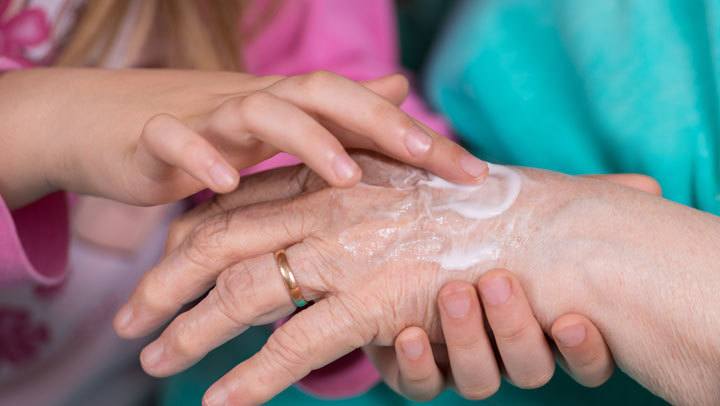Caretaker helping a resident apply lotion at Randall Residence of Auburn Hills in Auburn Hills, Michigan
