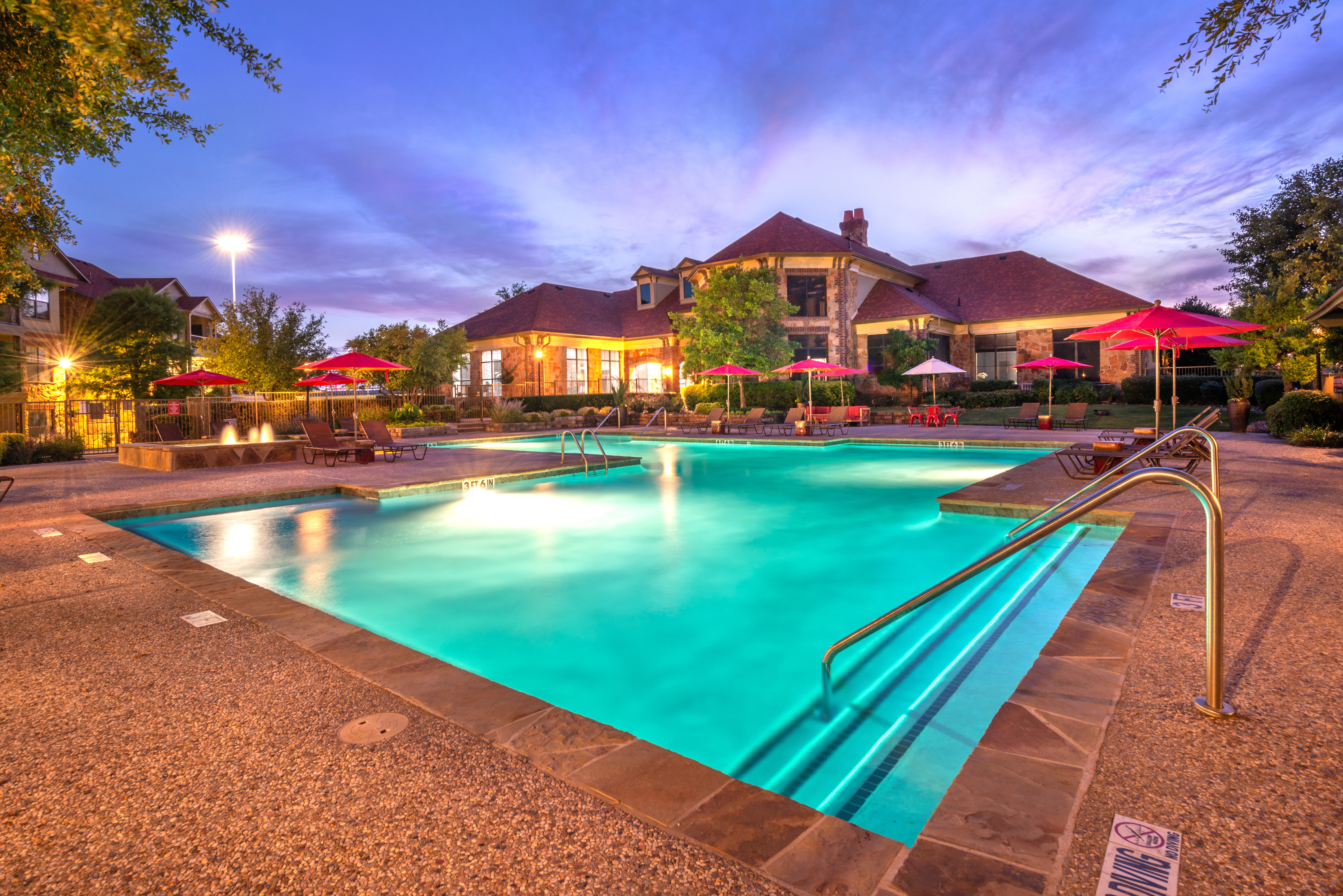 Resort-style swimming pool with a fountain nearby at Olympus Team Ranch in Benbrook, Texas