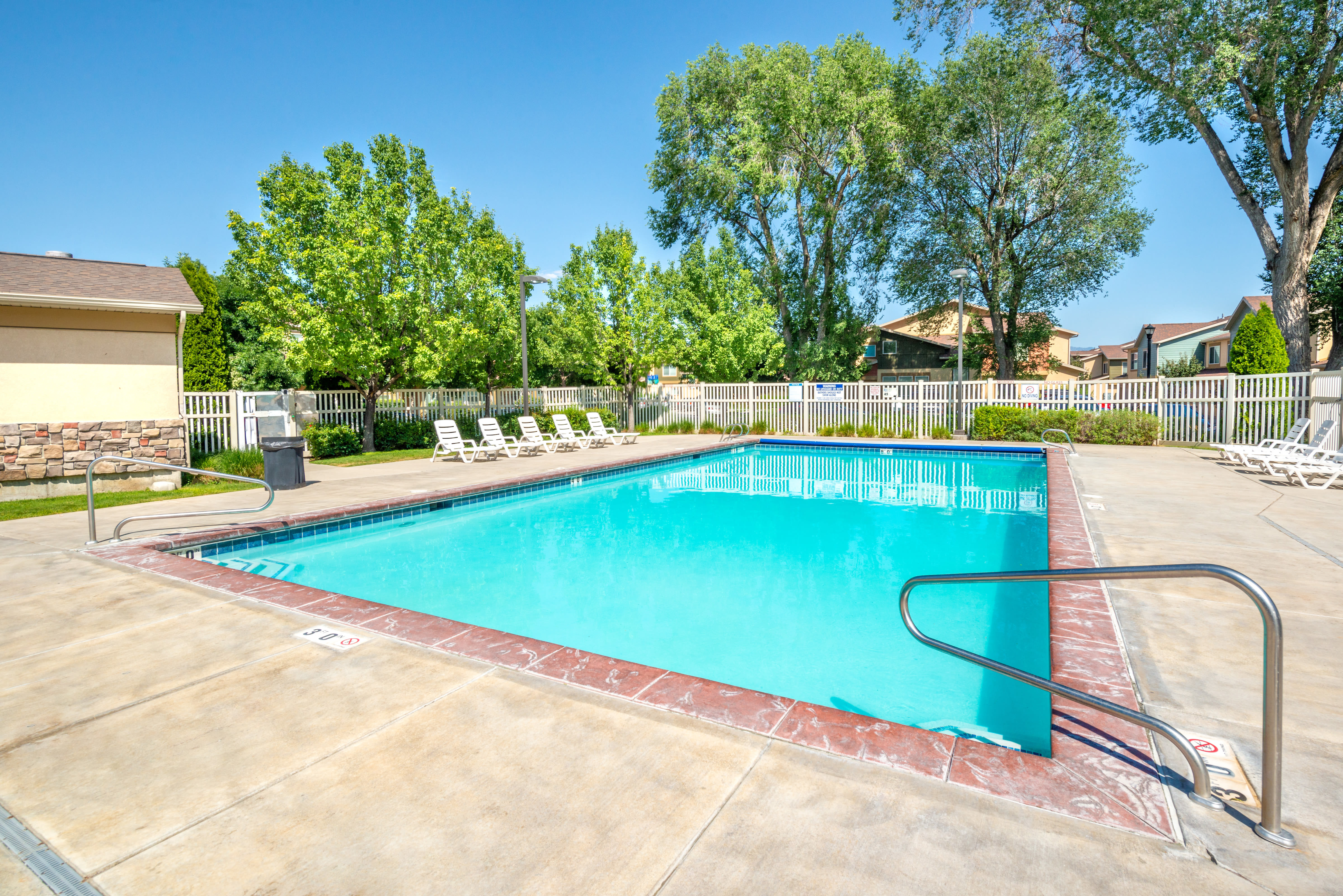 Community pool with mature trees in the background at Olympus at the District in South Jordan, Utah