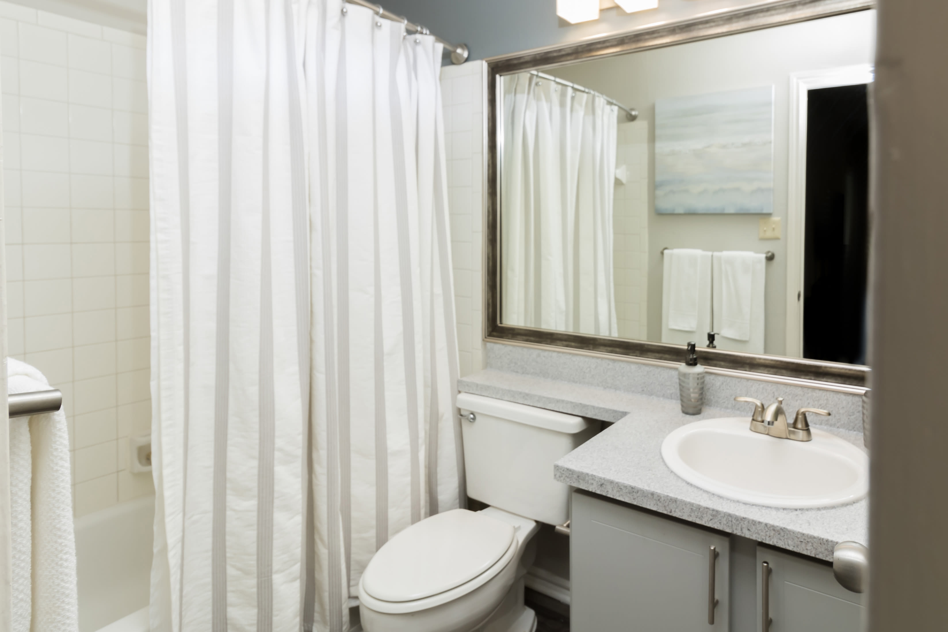 Bathroom with large mirror and cute vanity at The Logan in Bedford, Texas