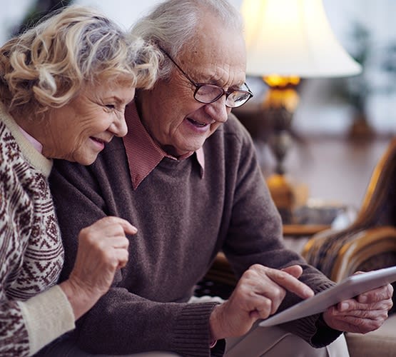 Senior couple ecstatic signing up for a tour at Grand Villa of Palm Coast in Palm Coast, Florida.