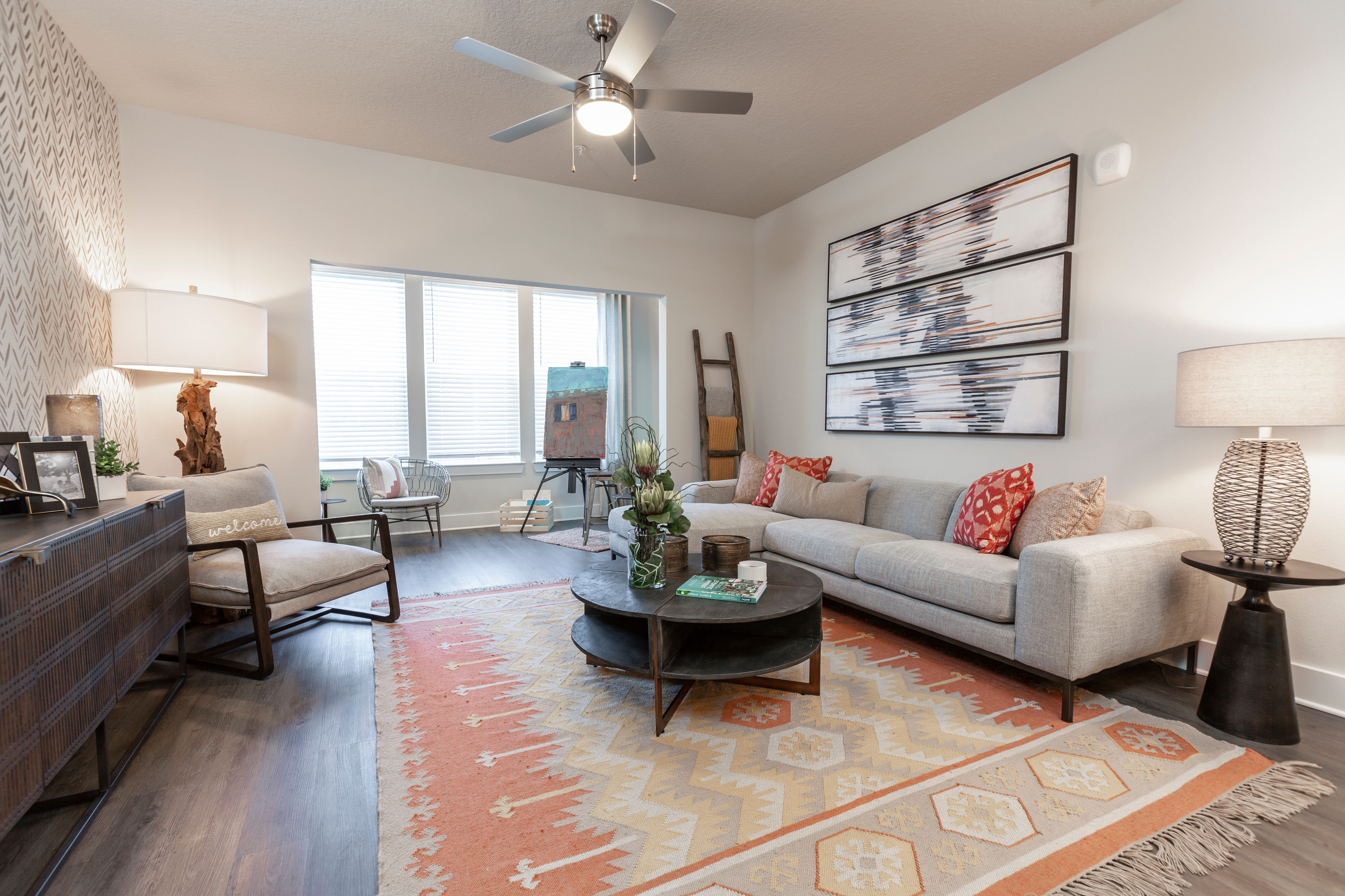 Well-furnished open-concept living area with hardwood floors and a ceiling fan in a model home at Parc at Wesley Chapel in Wesley Chapel, Florida