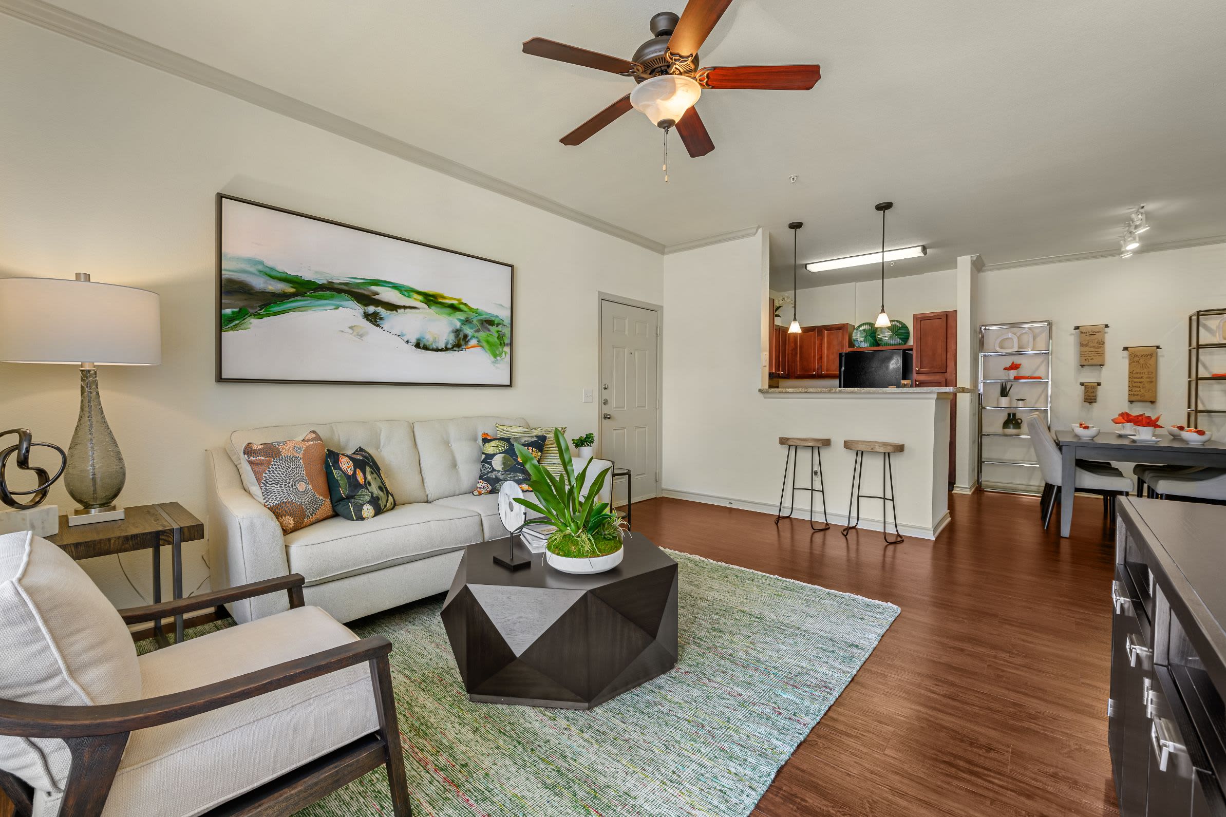 Living room with wood style floors and a large rug at Marquis Lakeline Station in Austin, Texas