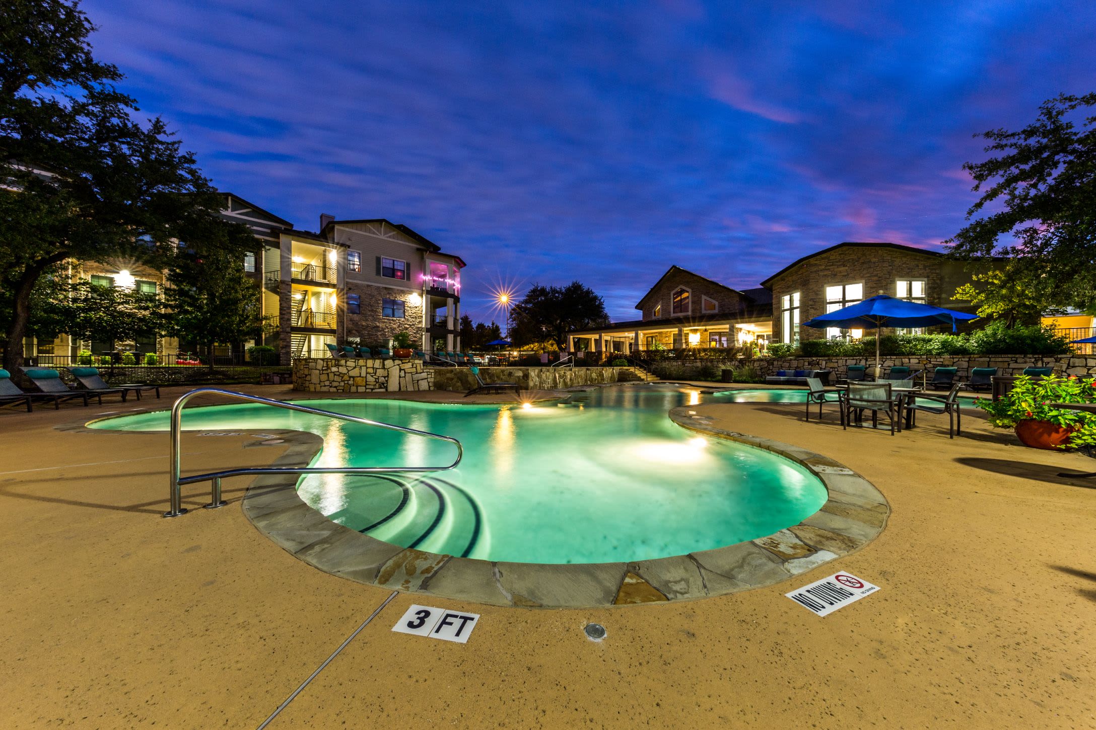 Well lit pool beneath purple skies at Marquis on Lakeline in Cedar Park, Texas