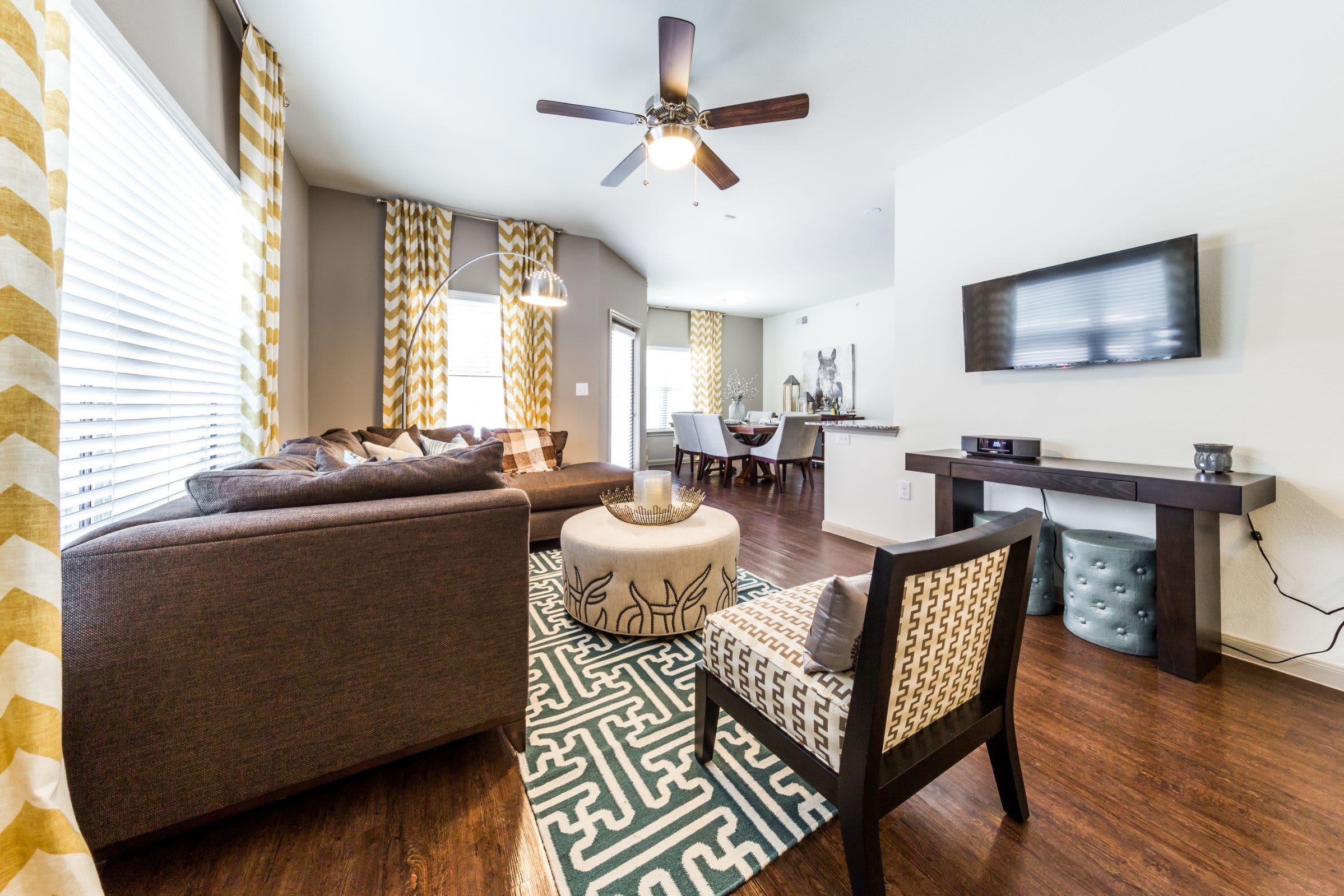 Bright living room with wood flooring and a large rug at Marquis on Lakeline in Cedar Park, Texas