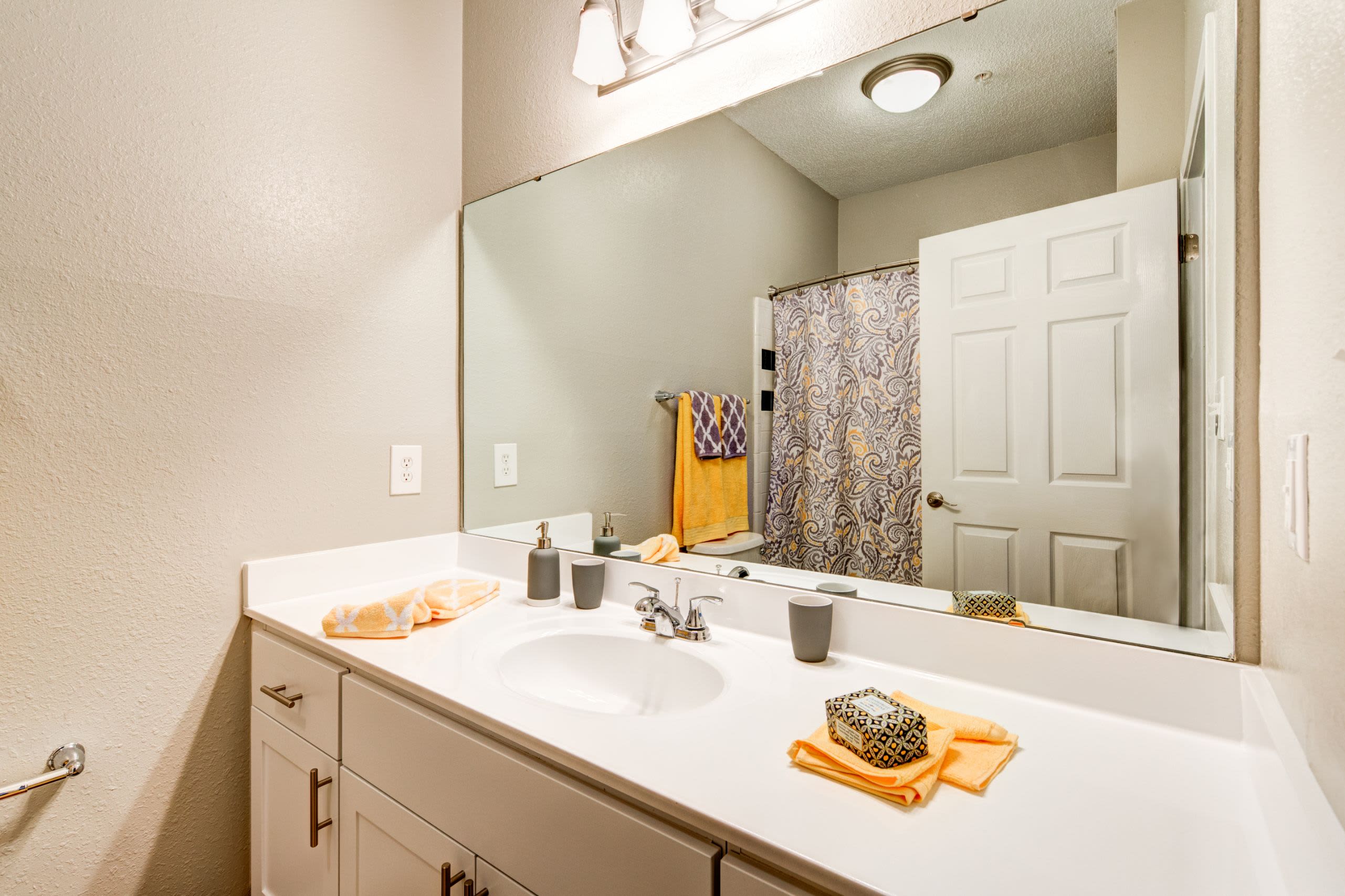 Bathroom with white cabinets and a large mirror at Marquis on Edwards Mill in Raleigh, North Carolina