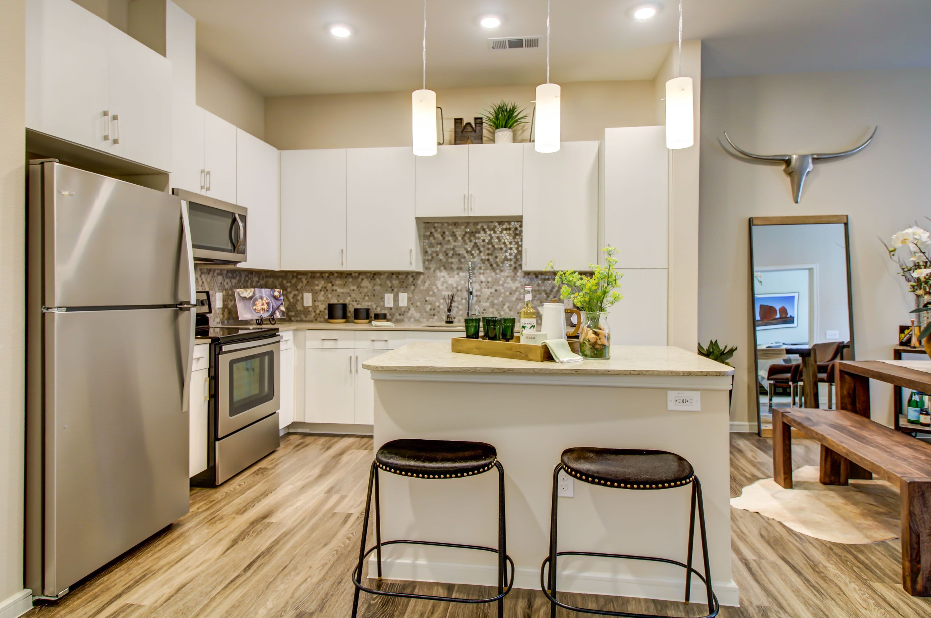 Modern kitchen with white cabinets and breakfast bar at Westerly 360 in Austin, Texas