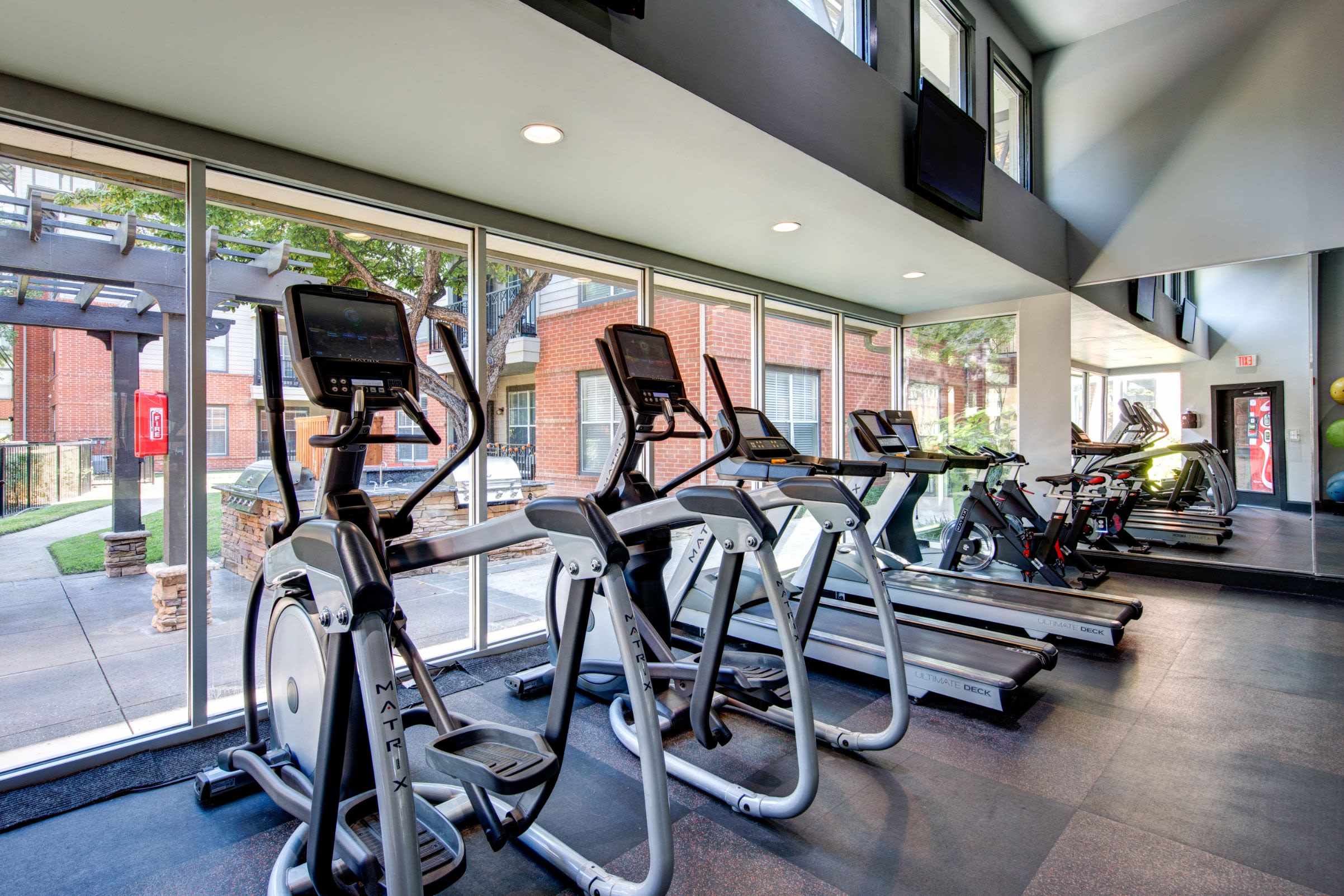 Cardio machines lined up near floor to ceiling windows at Marquis on Gaston in Dallas, Texas