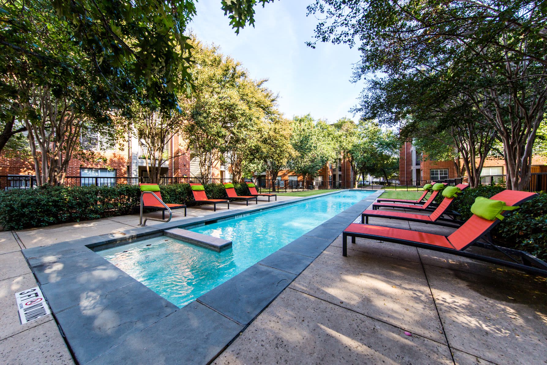 Long and skinny swimming pool surrounded by trees and lounge chairs at Marquis on Gaston in Dallas, Texas