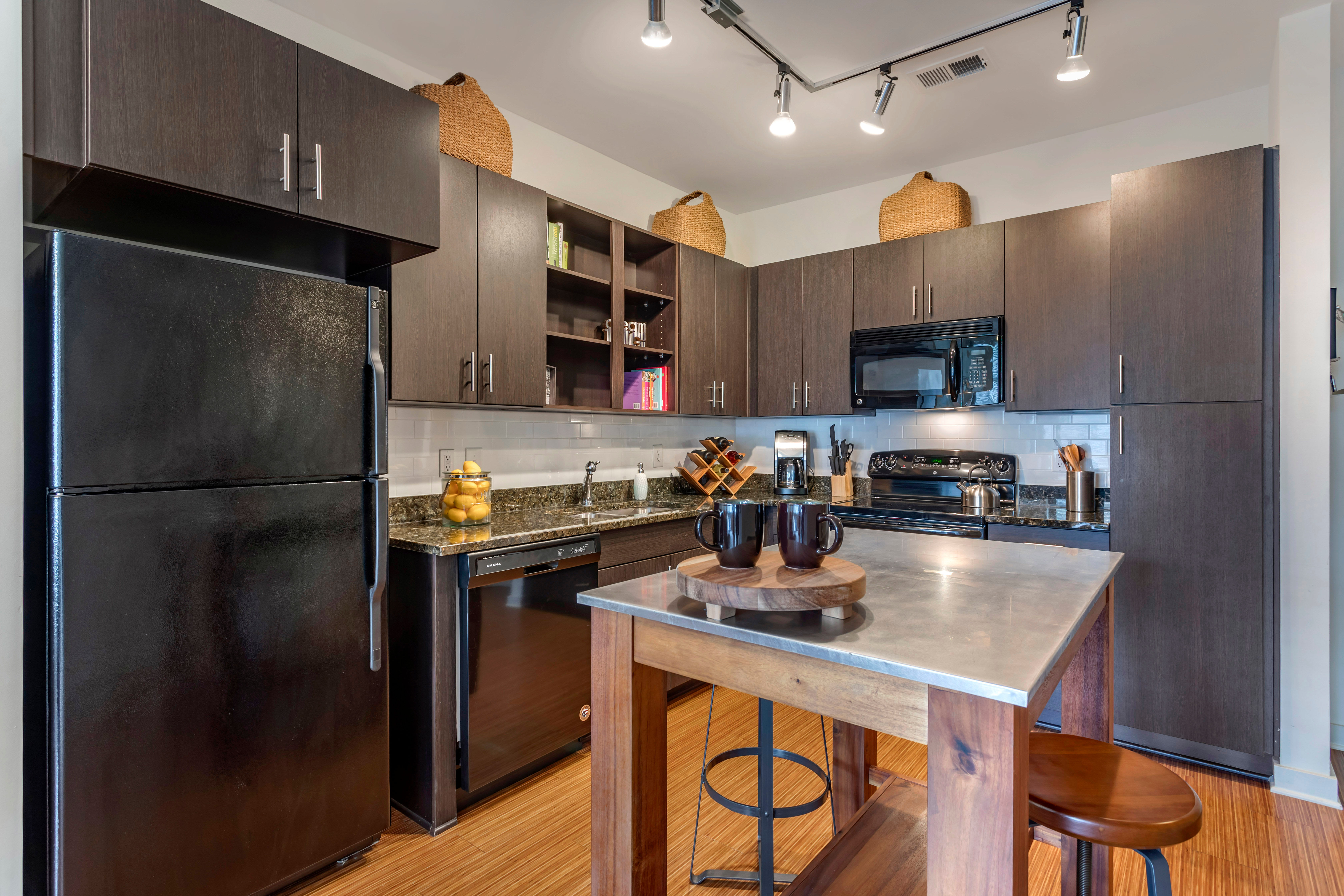 Large open-concept kitchen with an island and rich wood cabinetry in a model home at Olympus Midtown in Nashville, Tennessee