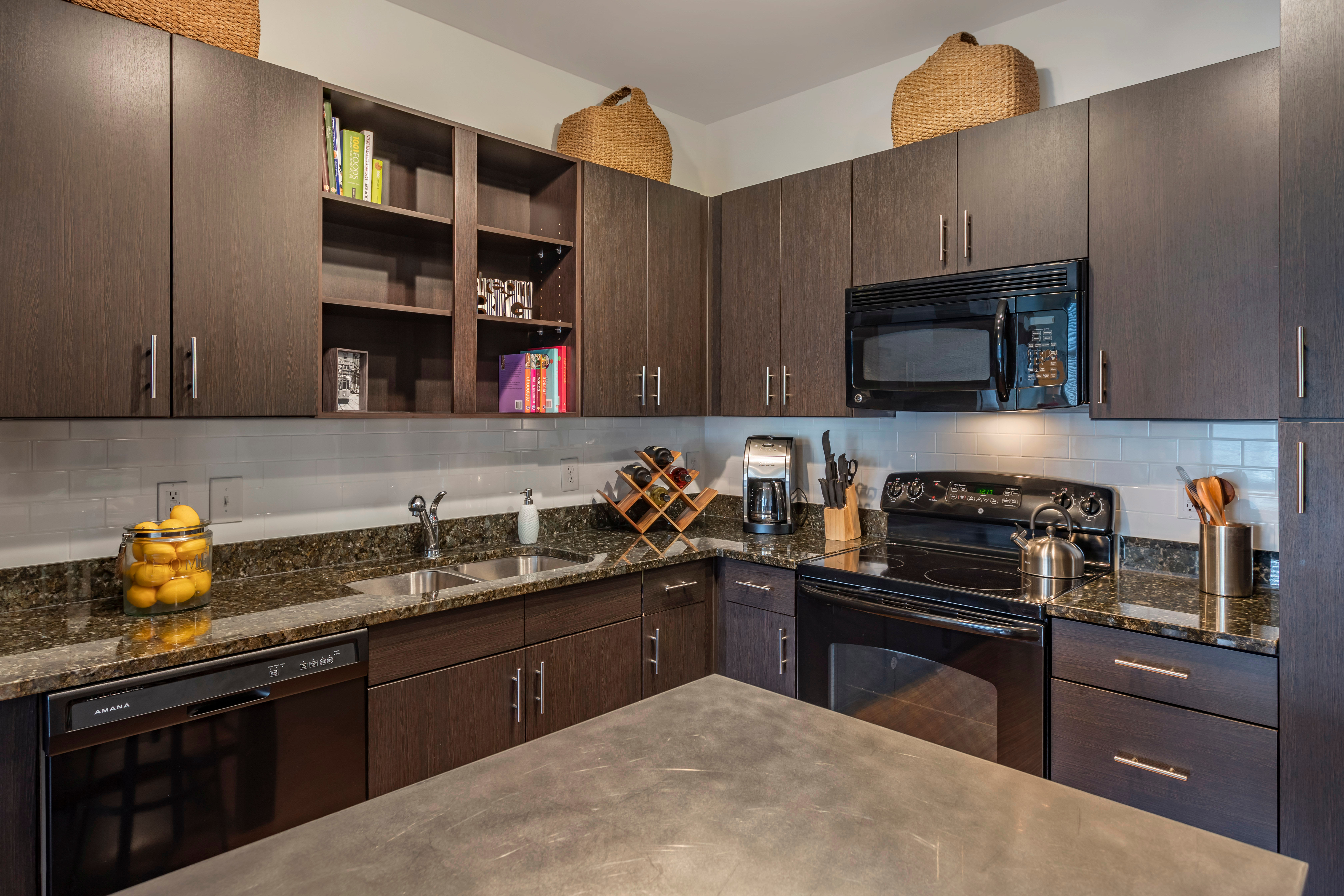 Open-concept gourmet kitchen with black appliances in a model apartment at Olympus Midtown in Nashville, Tennessee