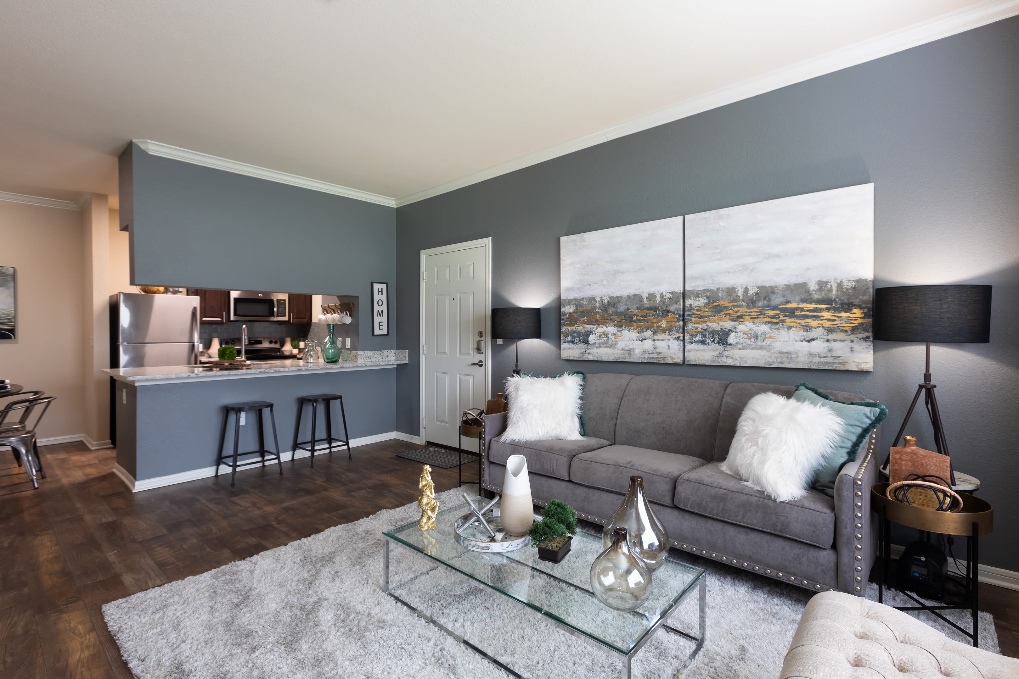 Open-concept floor plan with hardwood floors and accent wall in the living area of model home at Ranch at Hudson Xing in McKinney, Texas