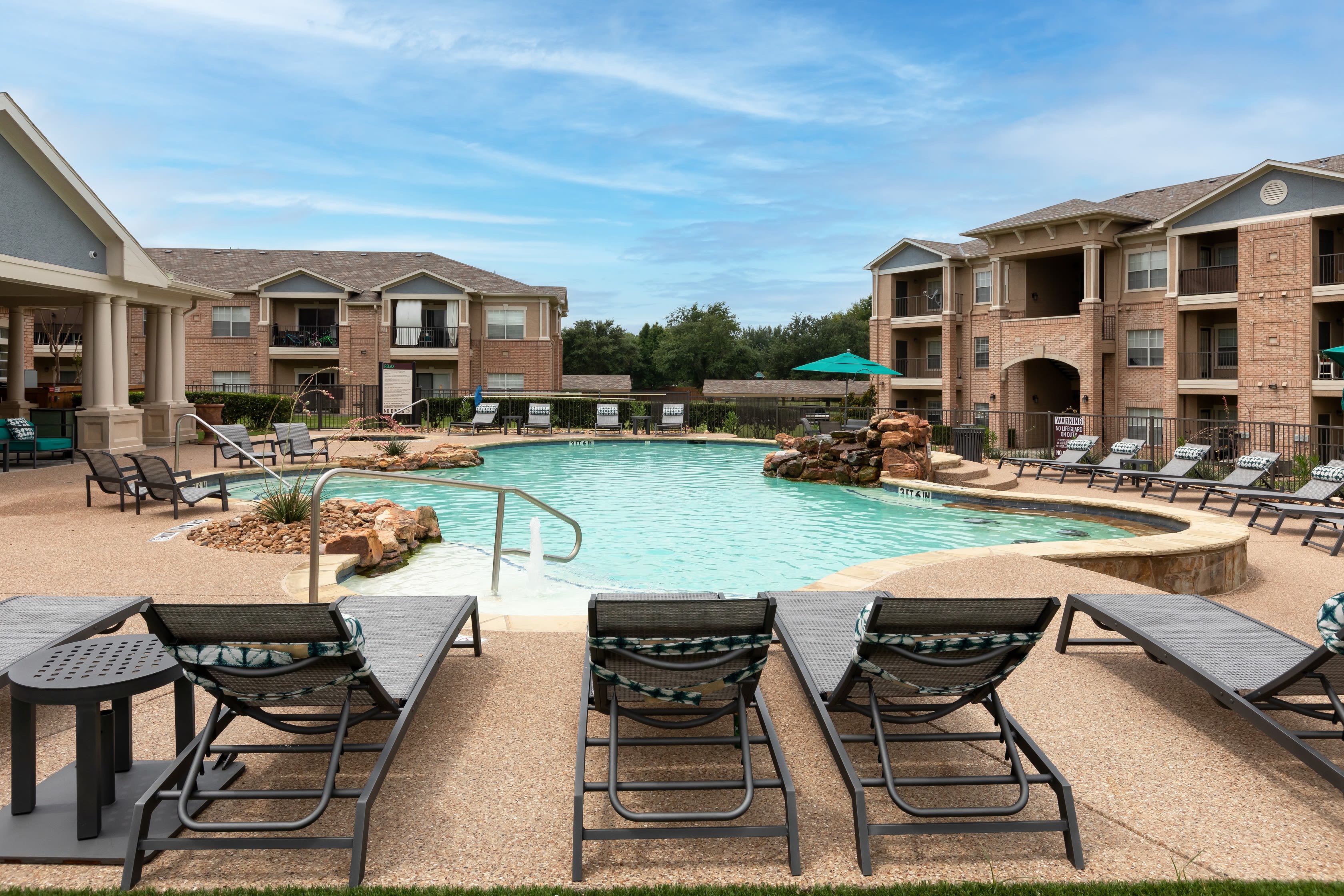 Swimming pool with a fountain on a sunny day at Ranch at Hudson Xing in McKinney, Texas