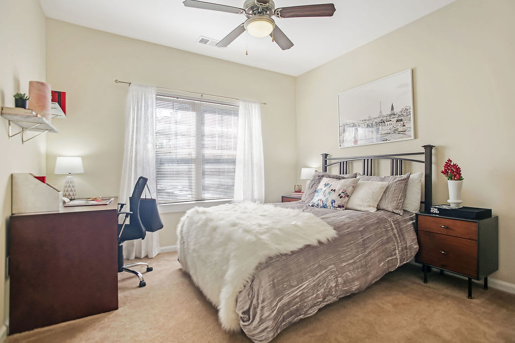 Model bedroom with a ceiling fan and plush carpeting at West 22 in Kennesaw, Georgia