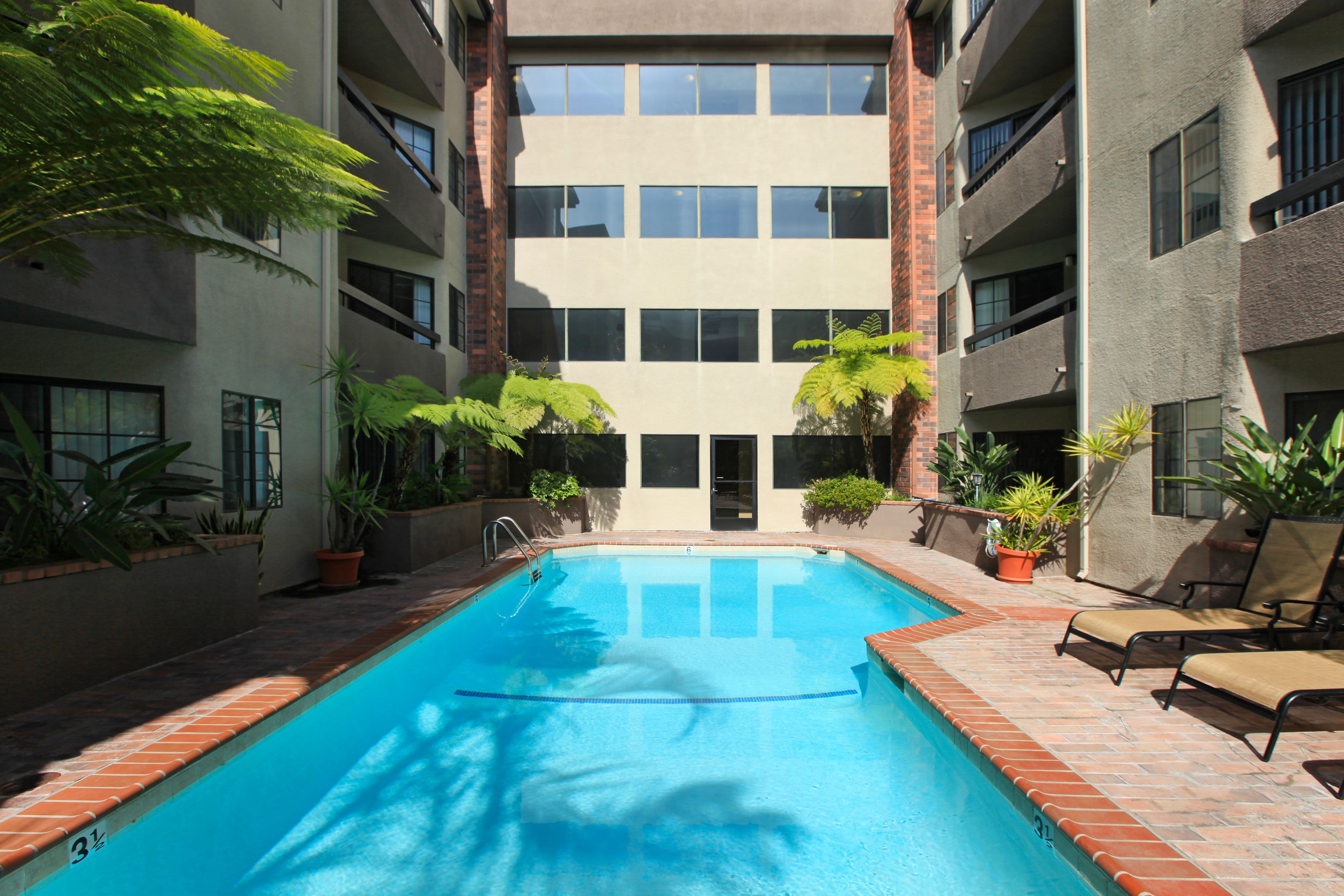 Sparkling pool with lounge chairs at Savoy West Apartments in Los Angeles, California