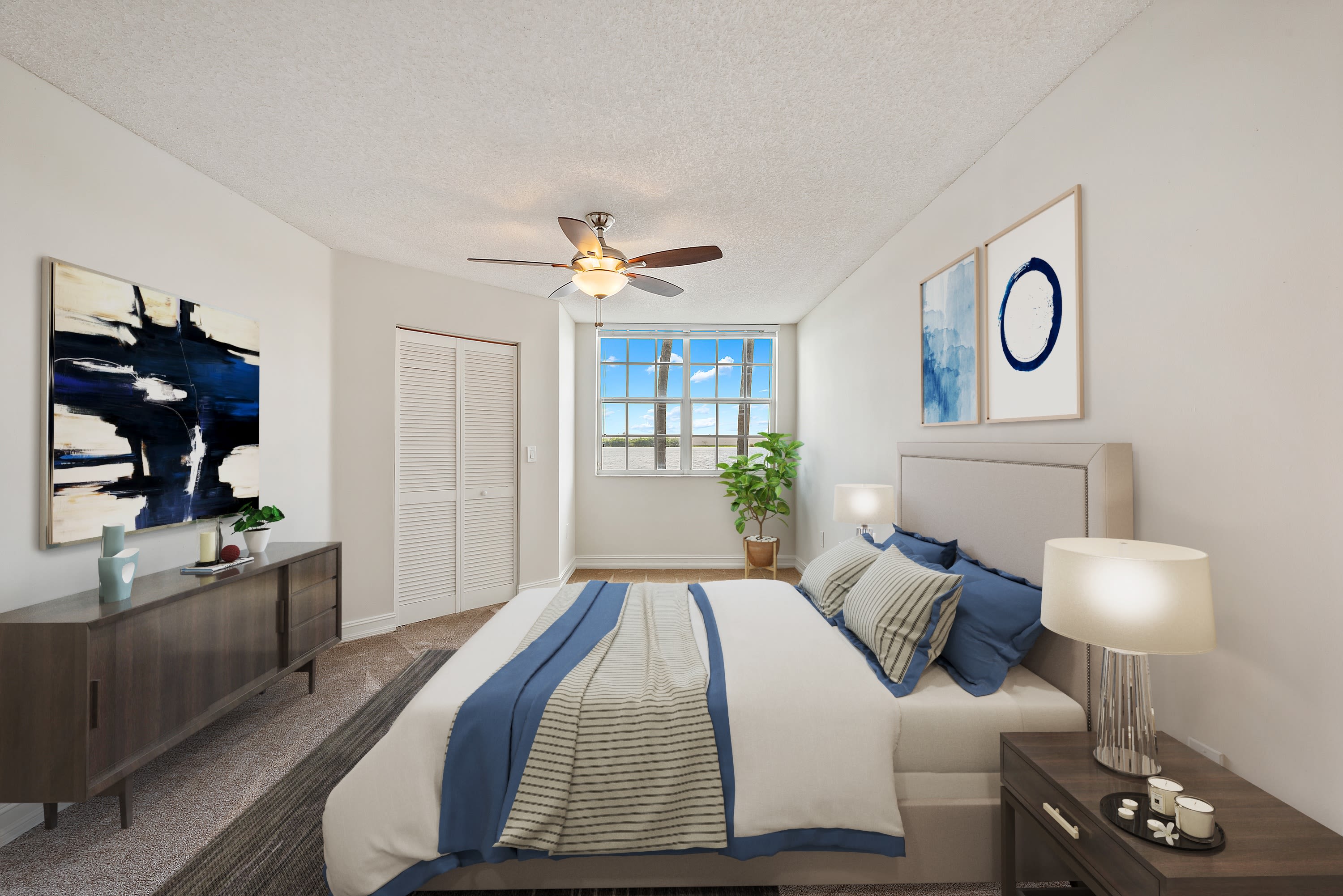 Beautiful model bedroom with a ceiling fan and plush carpeting at St. Tropez Apartments in Miami Lakes, Florida