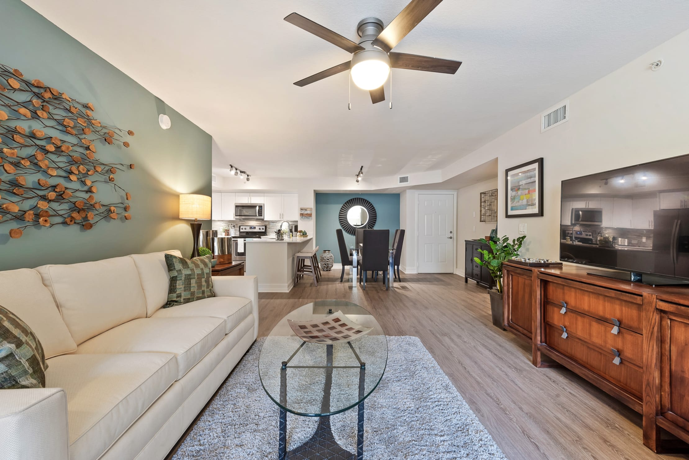 Spacious model living room with wood-style flooring opening onto a private balcony at Crescent House Apartments in Miami Lakes, Florida