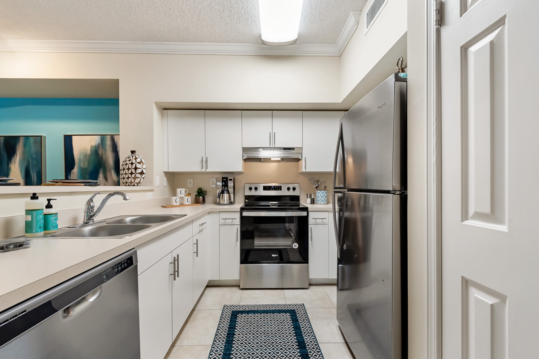 Brightly lit kitchen with stainless steel appliances, white cabinetry, and granite countertops at Fountain House Apartments in Miami Lakes, Florida