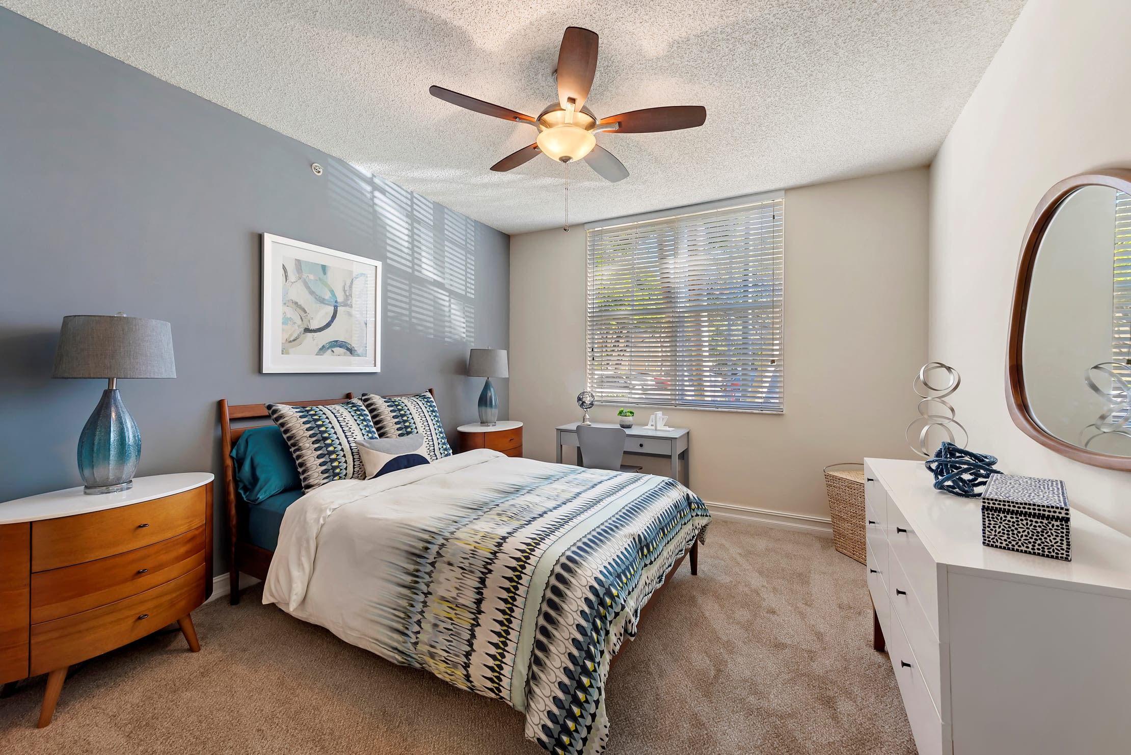 Well decorated model bedroom with plush carpeting and a ceiling fan at Fountain House Apartments in Miami Lakes, Florida