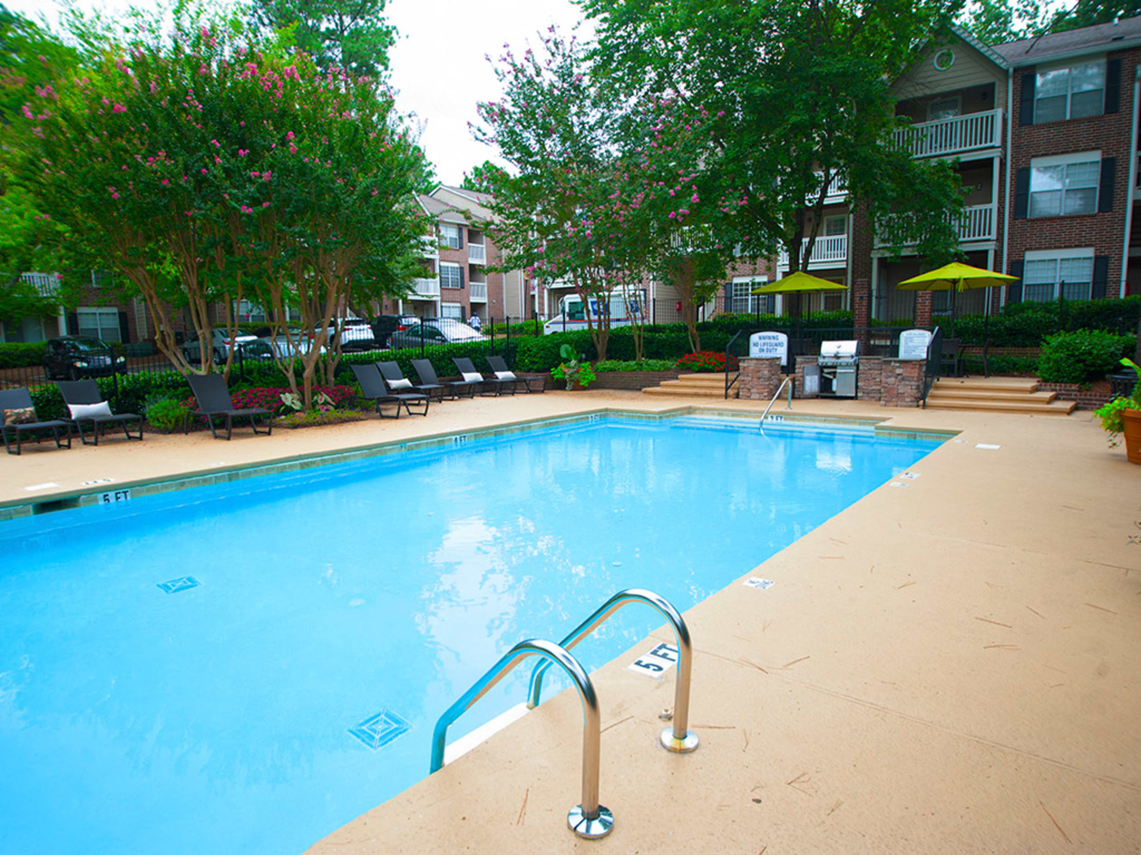 Swimming pool surrounded by lounge chairs and tables with umbrellas at Castlegate Collier Hills in Atlanta, Georgia