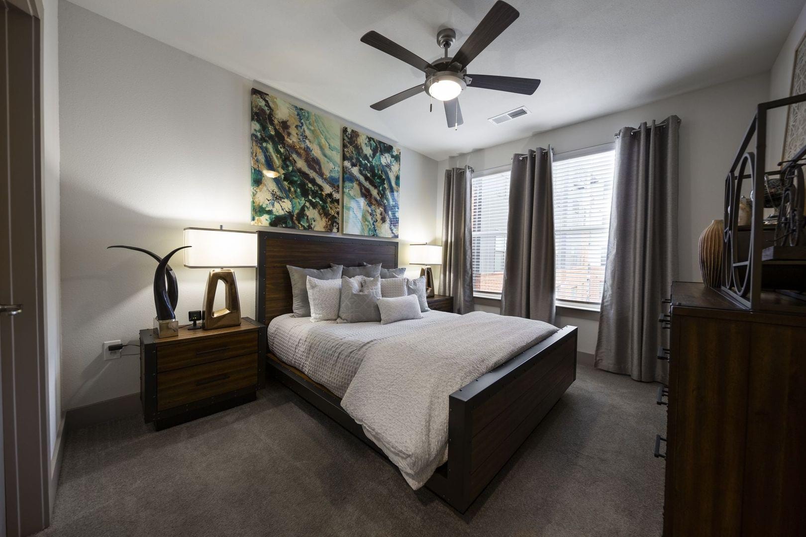 Elegant model master bedroom with plush carpeting and a ceiling fan at Steelyard in Oklahoma City, Oklahoma