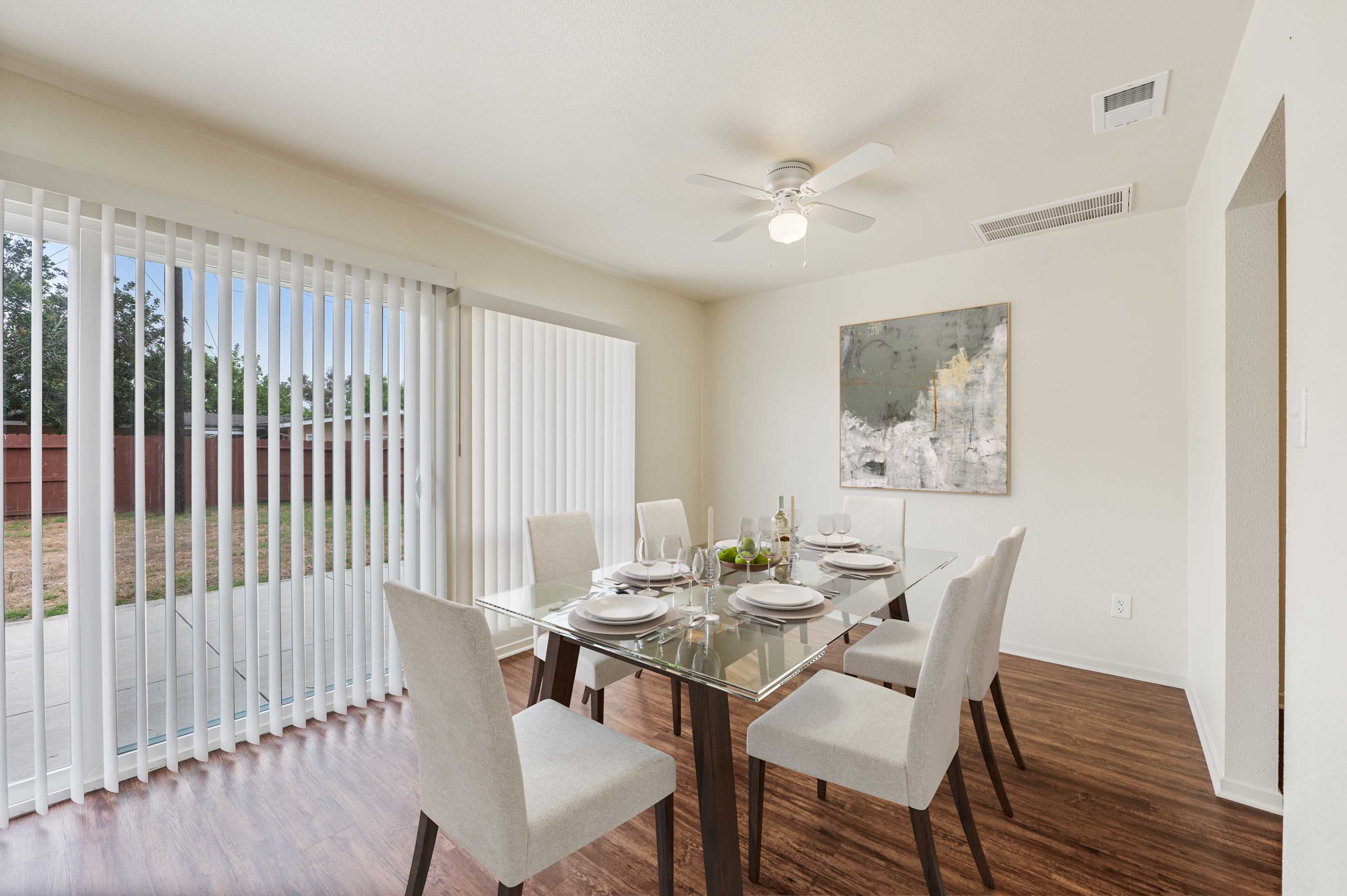 A dining room with wood floors and large windows at Coral Sea Cove in Port Hueneme, California