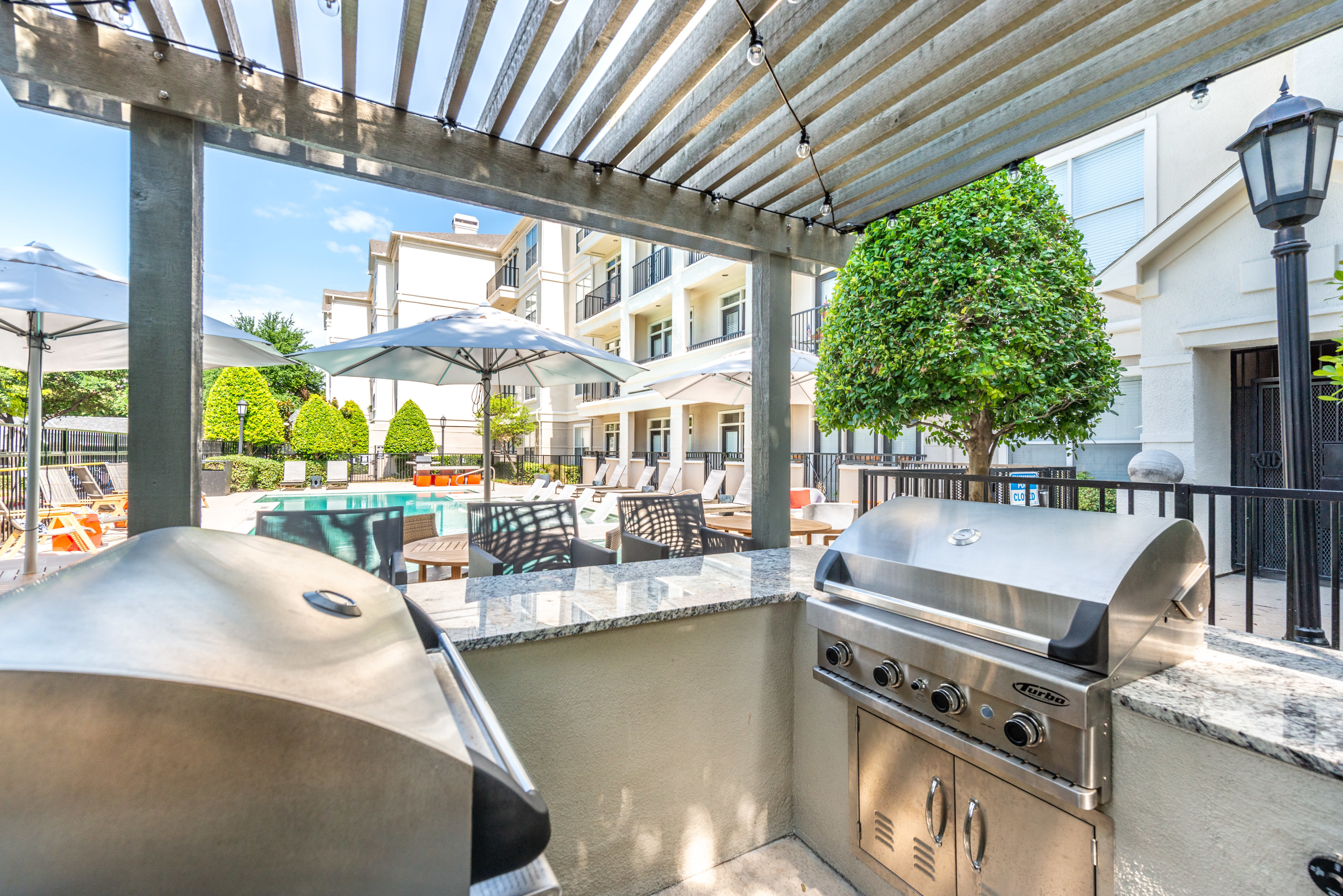 Poolside lounge area and grilling stations at 75 West in Dallas, Texas