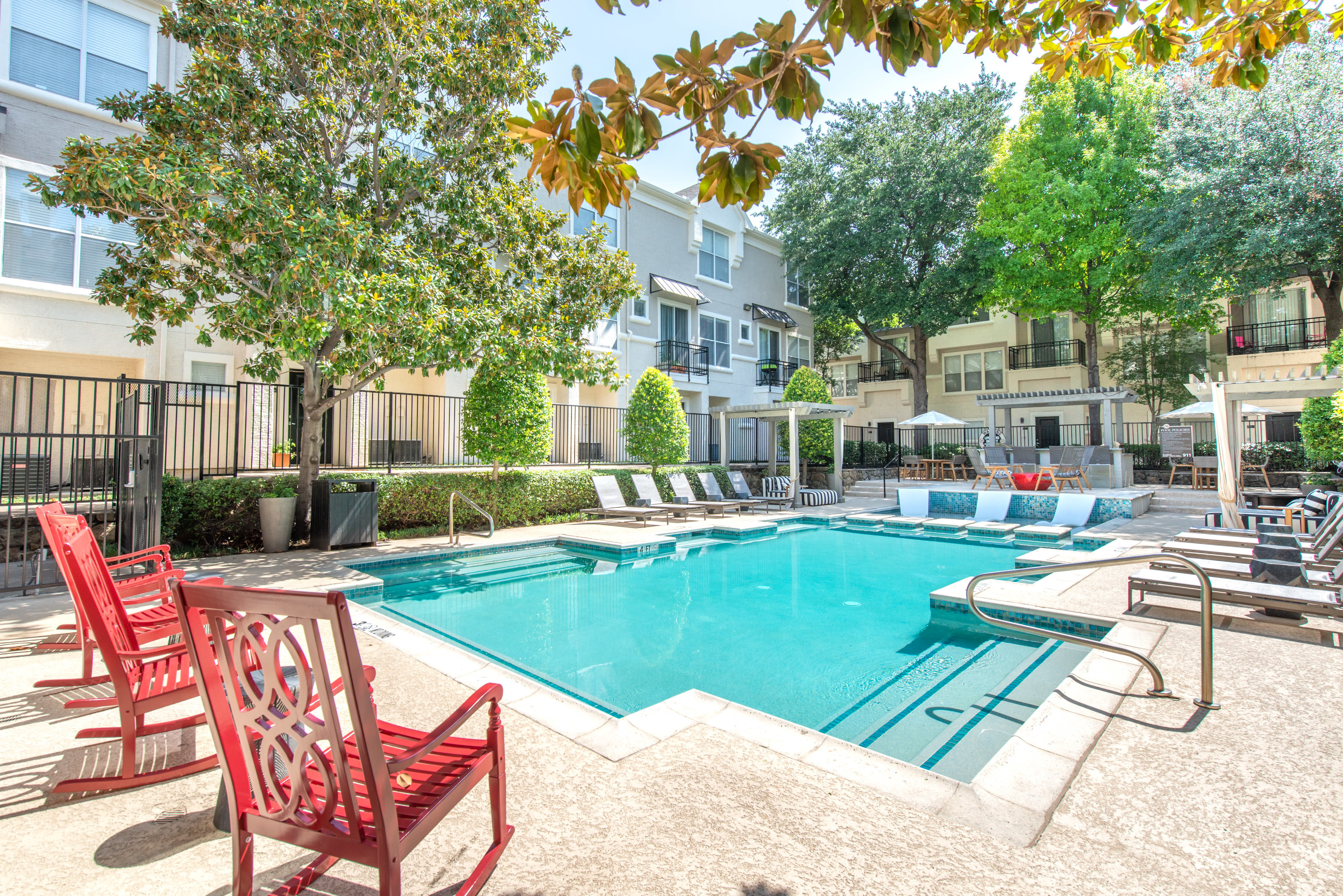Swimming pool with sundeck and poolside rocking chairs at 75 West in Dallas, Texas