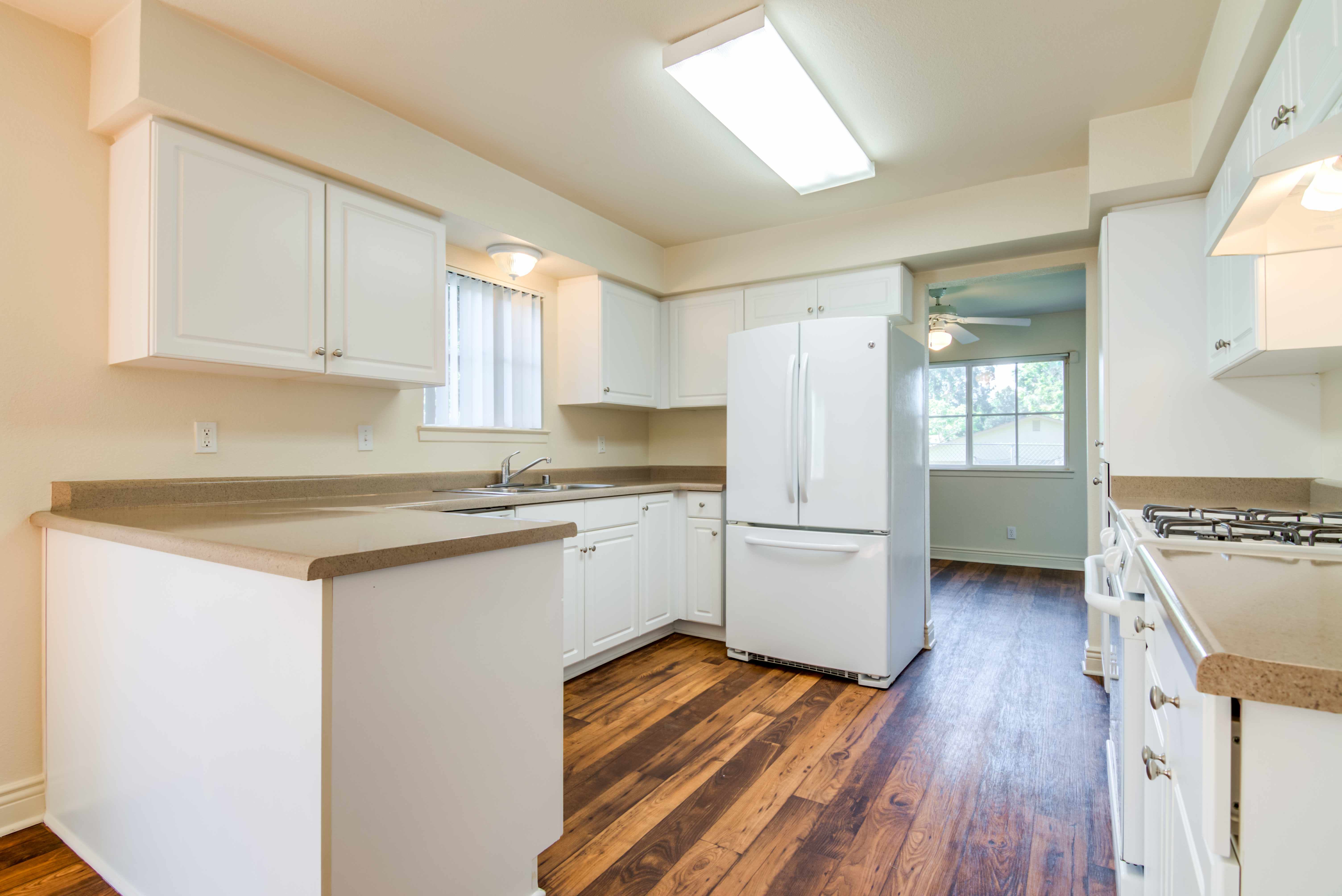 A kitchen with wood flooring and a fridge in a home at O'Neill Heights in Oceanside, California
