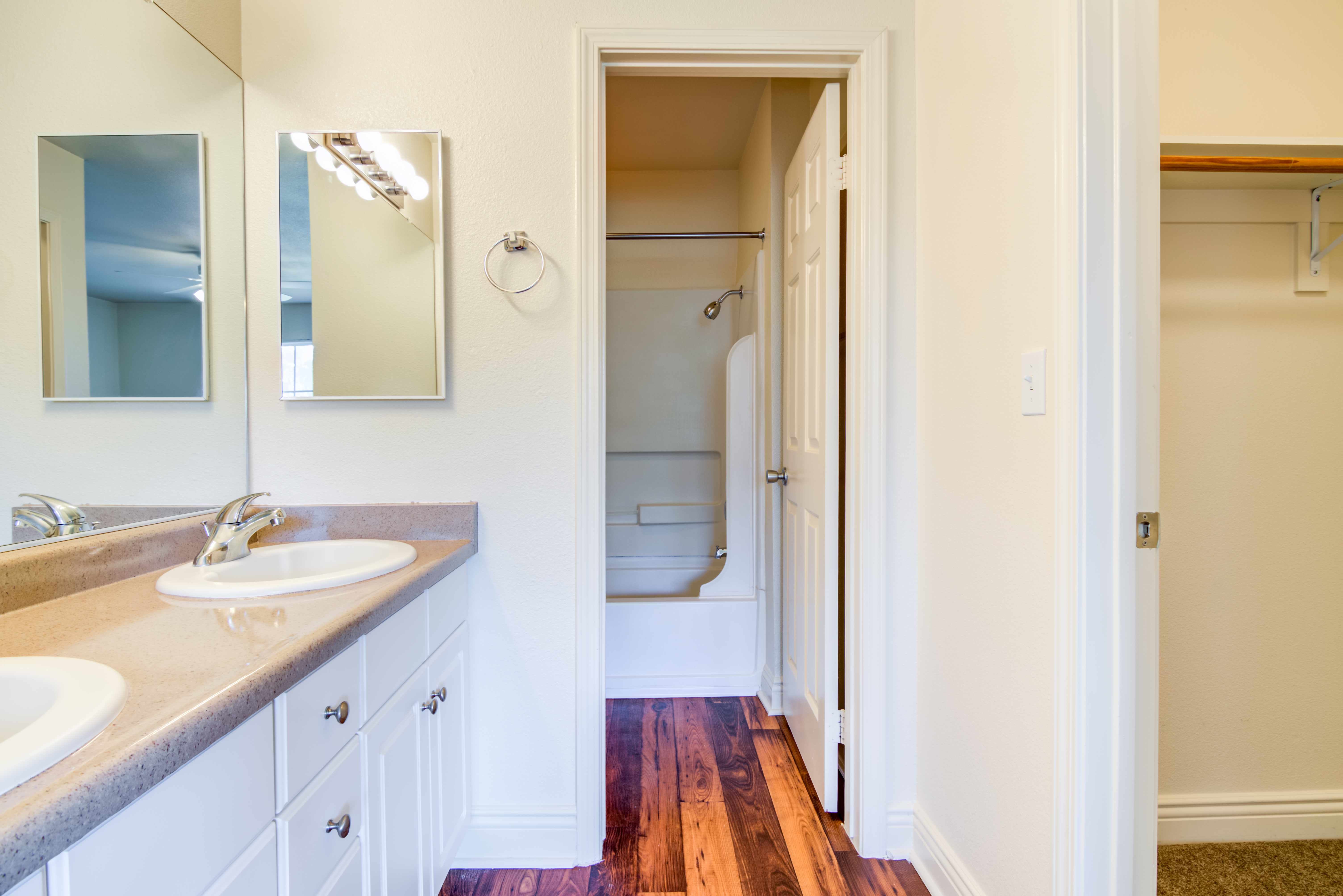 A bathroom with dual sinks and an adjacent storage closet at O'Neill Heights in Oceanside, California