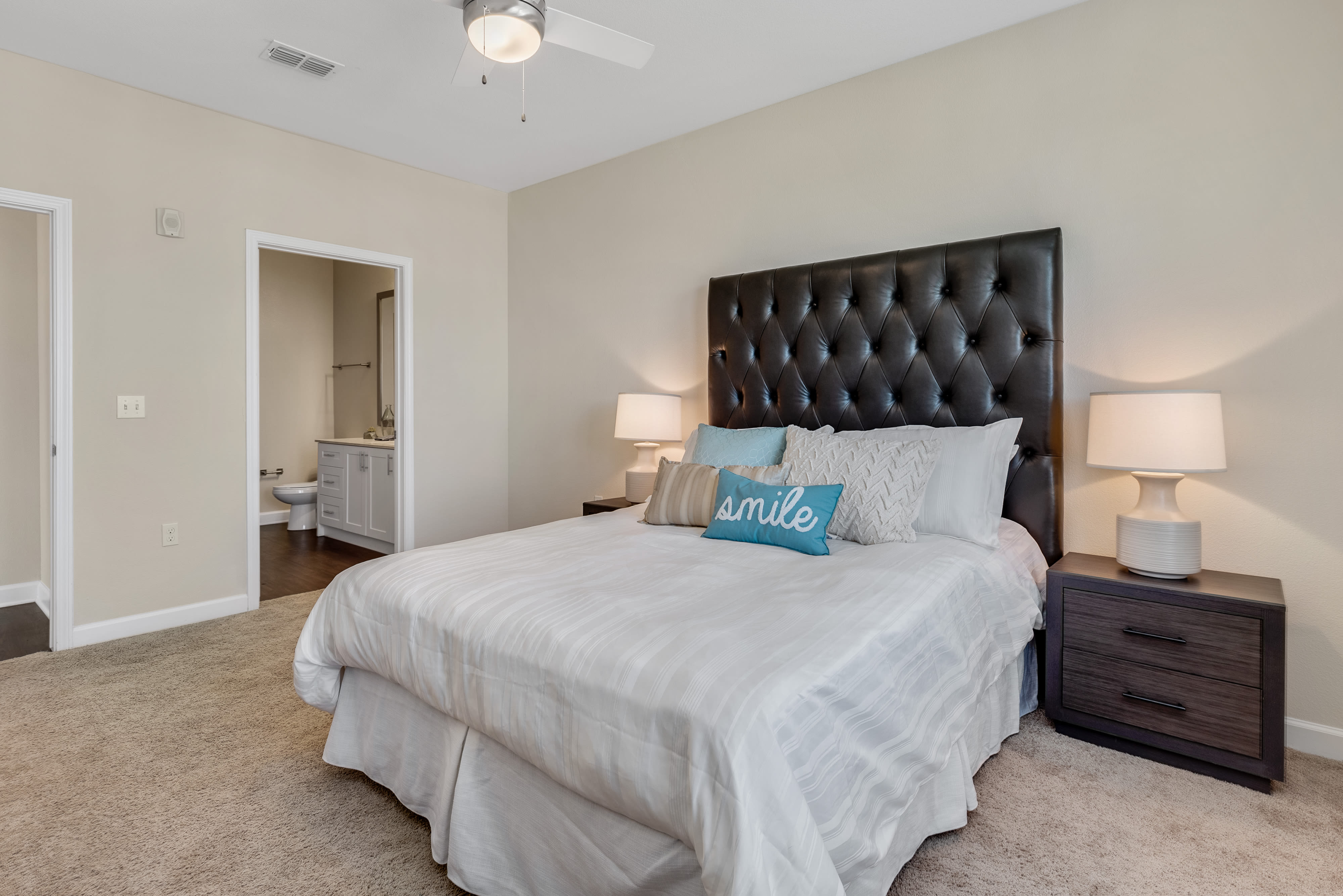 Model bedroom with plush carpeting and ensuite bathroom at The Point at Town Center in Jacksonville, Florida