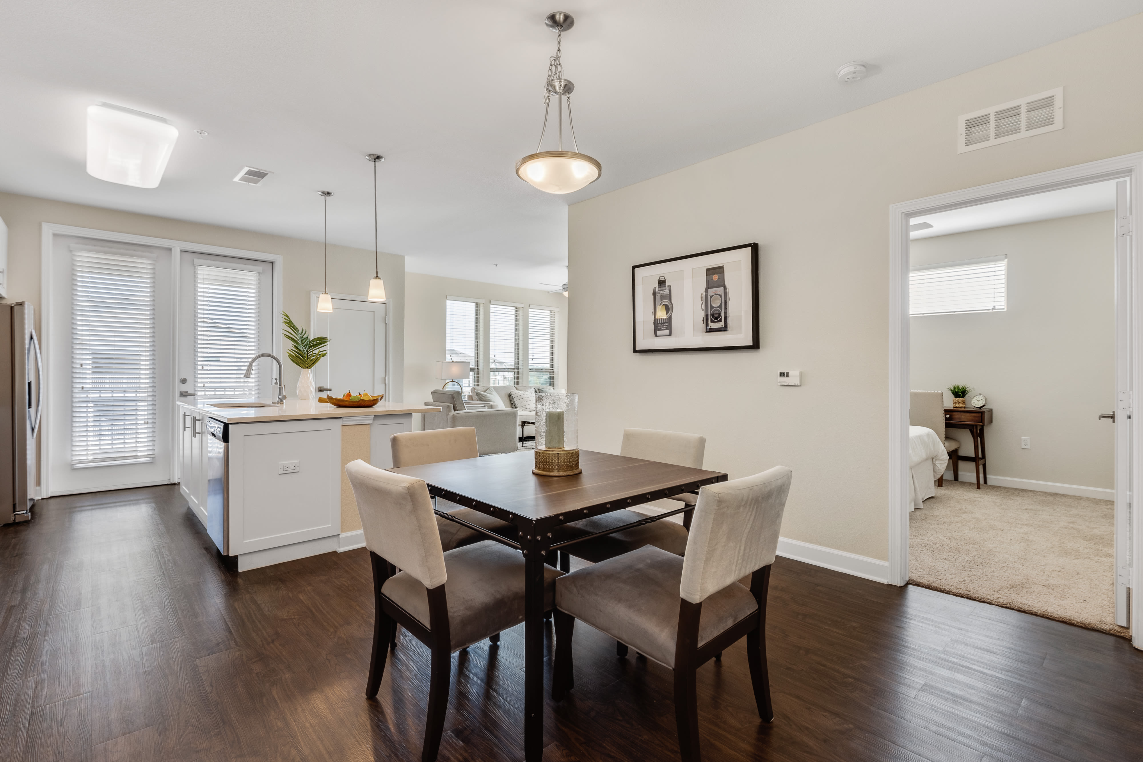 Model dining room and kitchen with wood-style floors and designer lighting at The Point at Town Center in Jacksonville, Florida