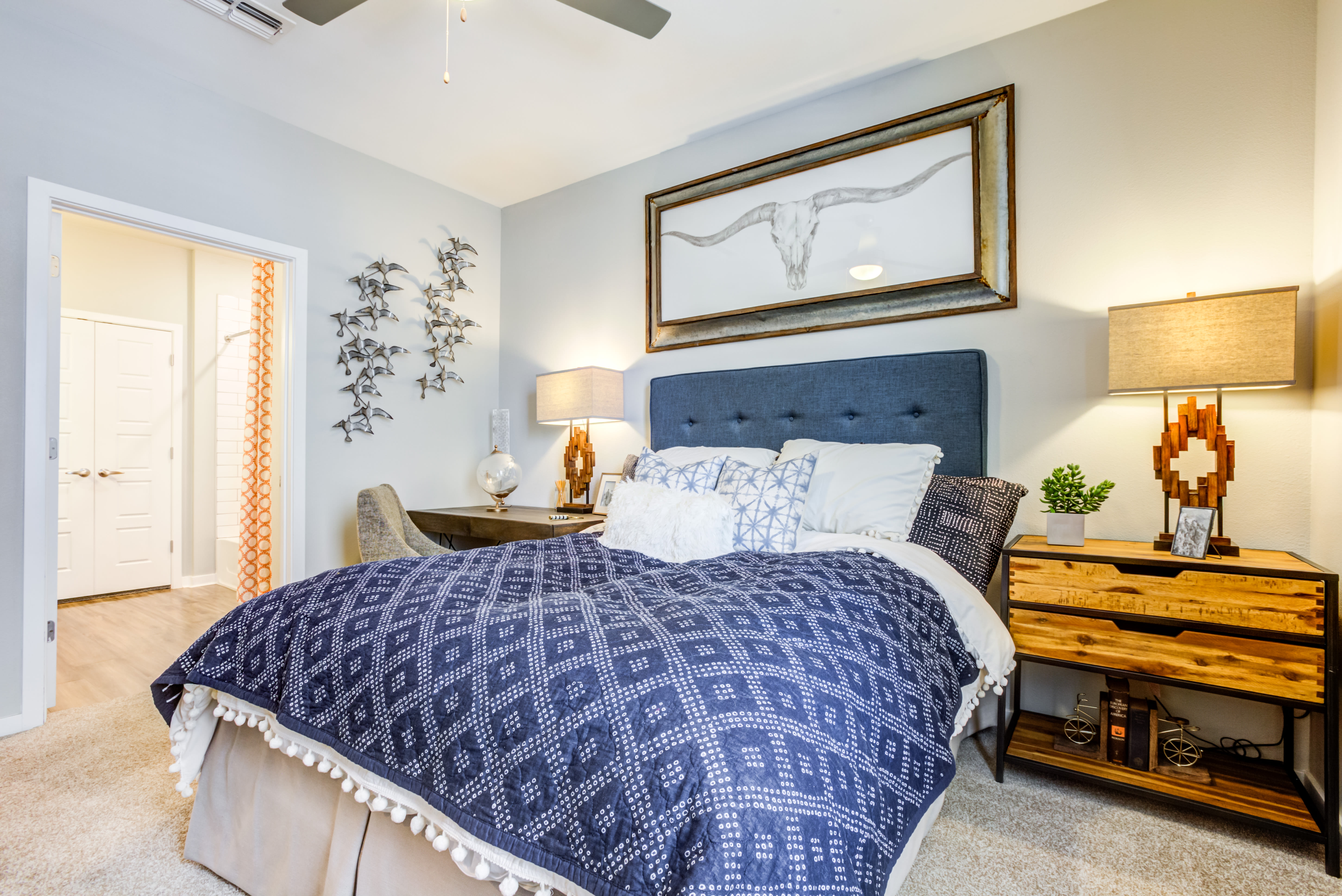 Model bedroom with plush carpeting and a ceiling fan at Town Commons in Gilbert, Arizona