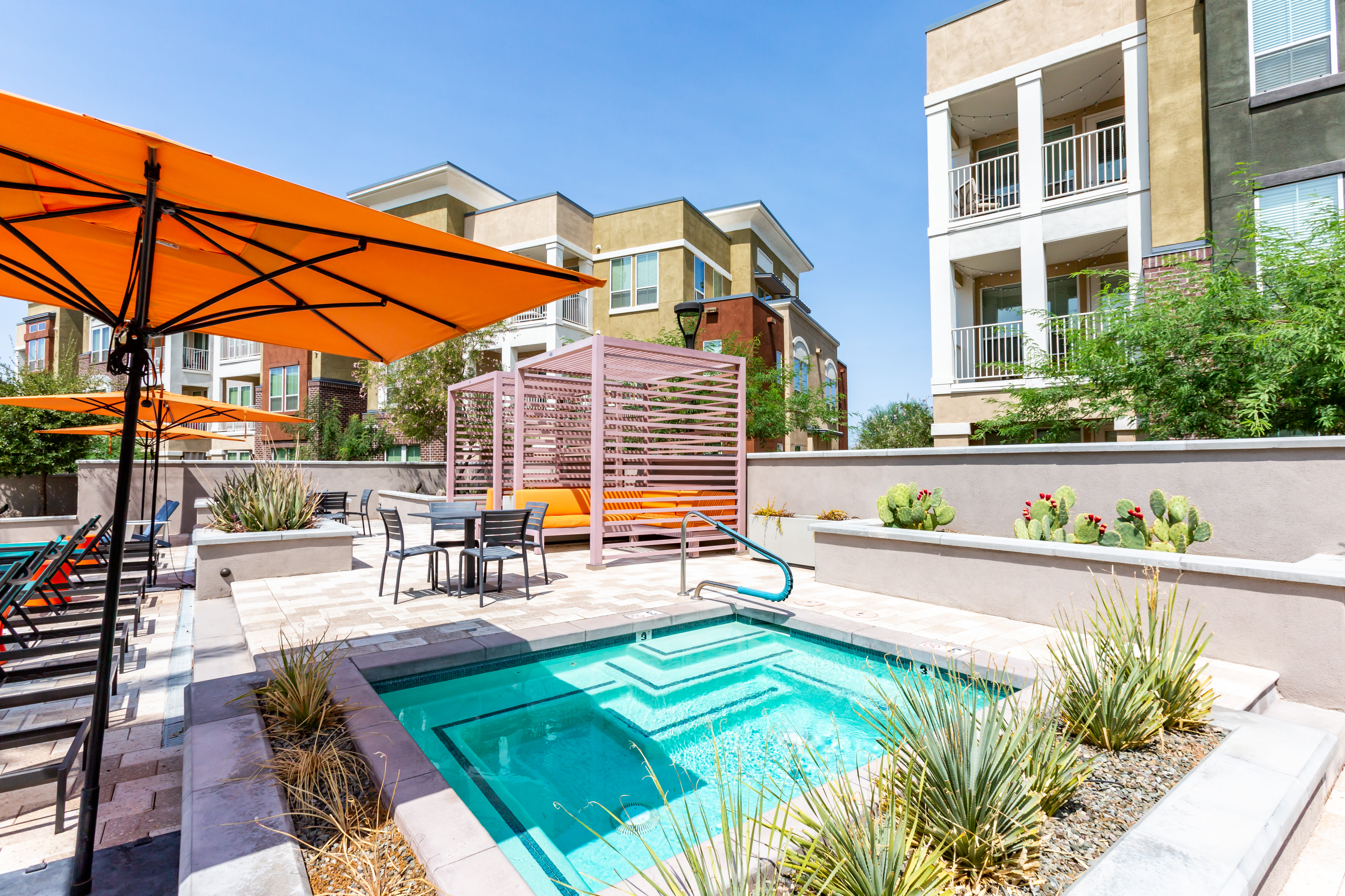 Children's splash area and sunny poolside cabana lounge seating at Town Commons in Gilbert, Arizona