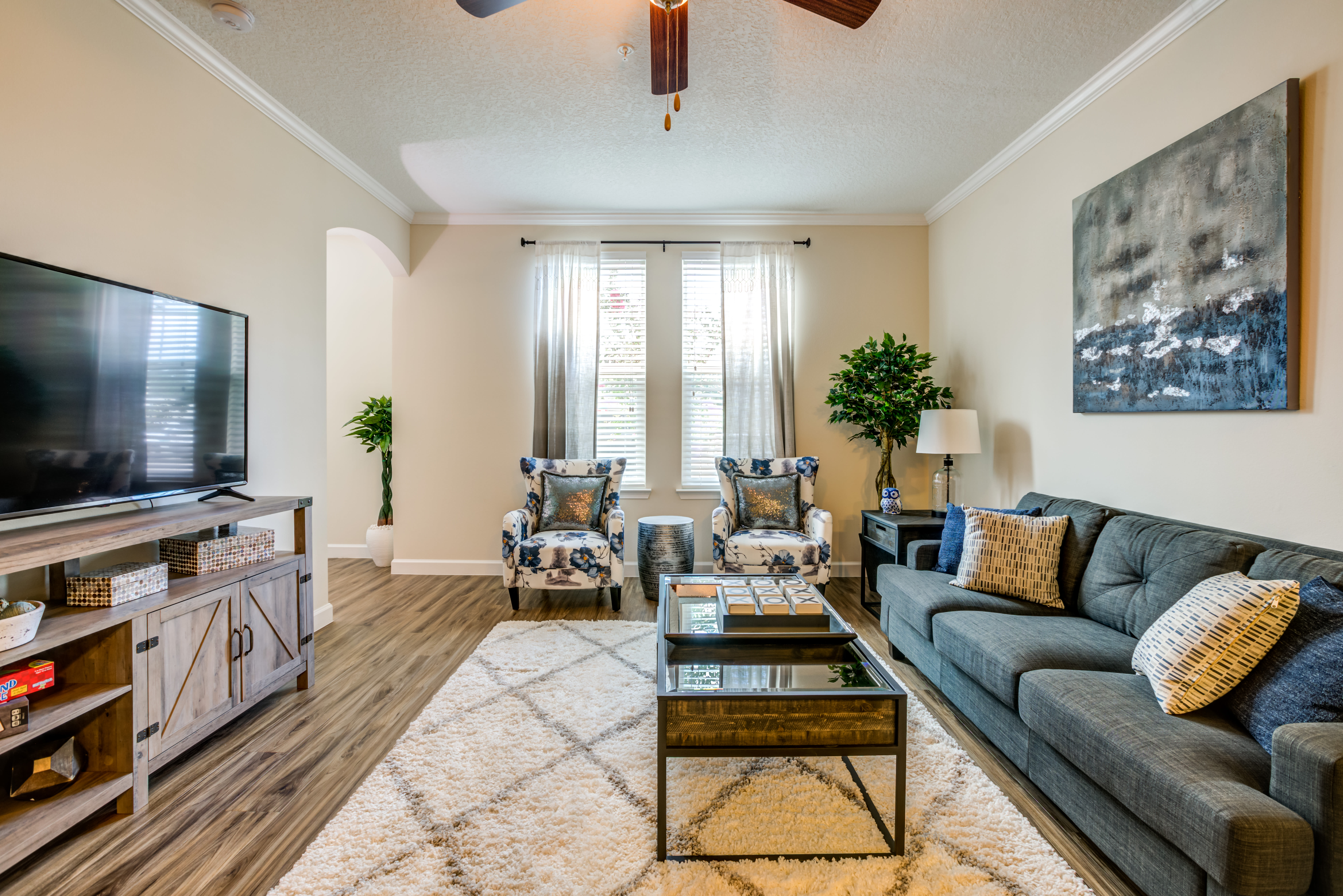 Model living room with wood-style floors and a ceiling fan at The Loop at 2800 in Sarasota, Florida