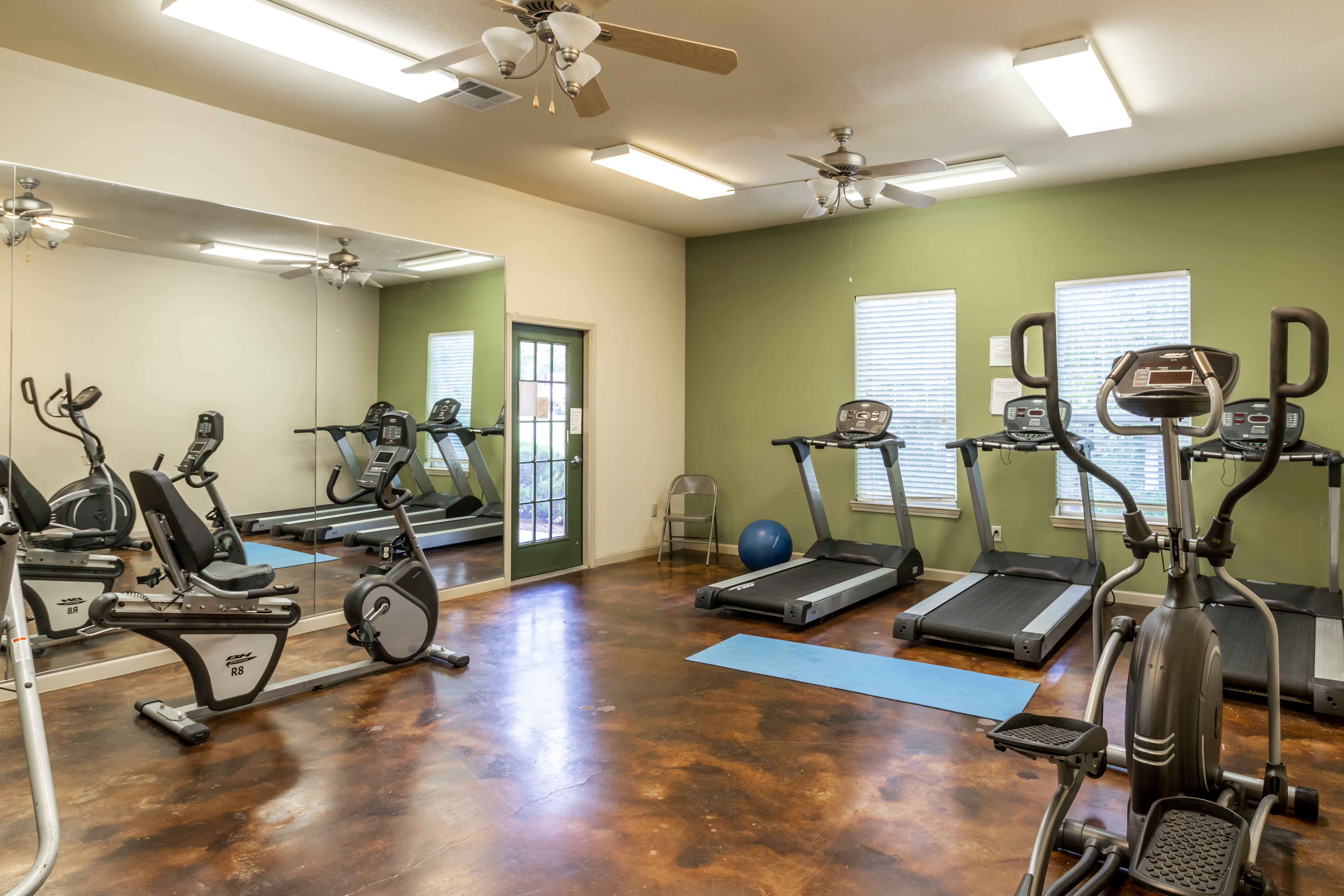 A fitness center with individual workout stations at Woodside Manor in Conroe, Texas