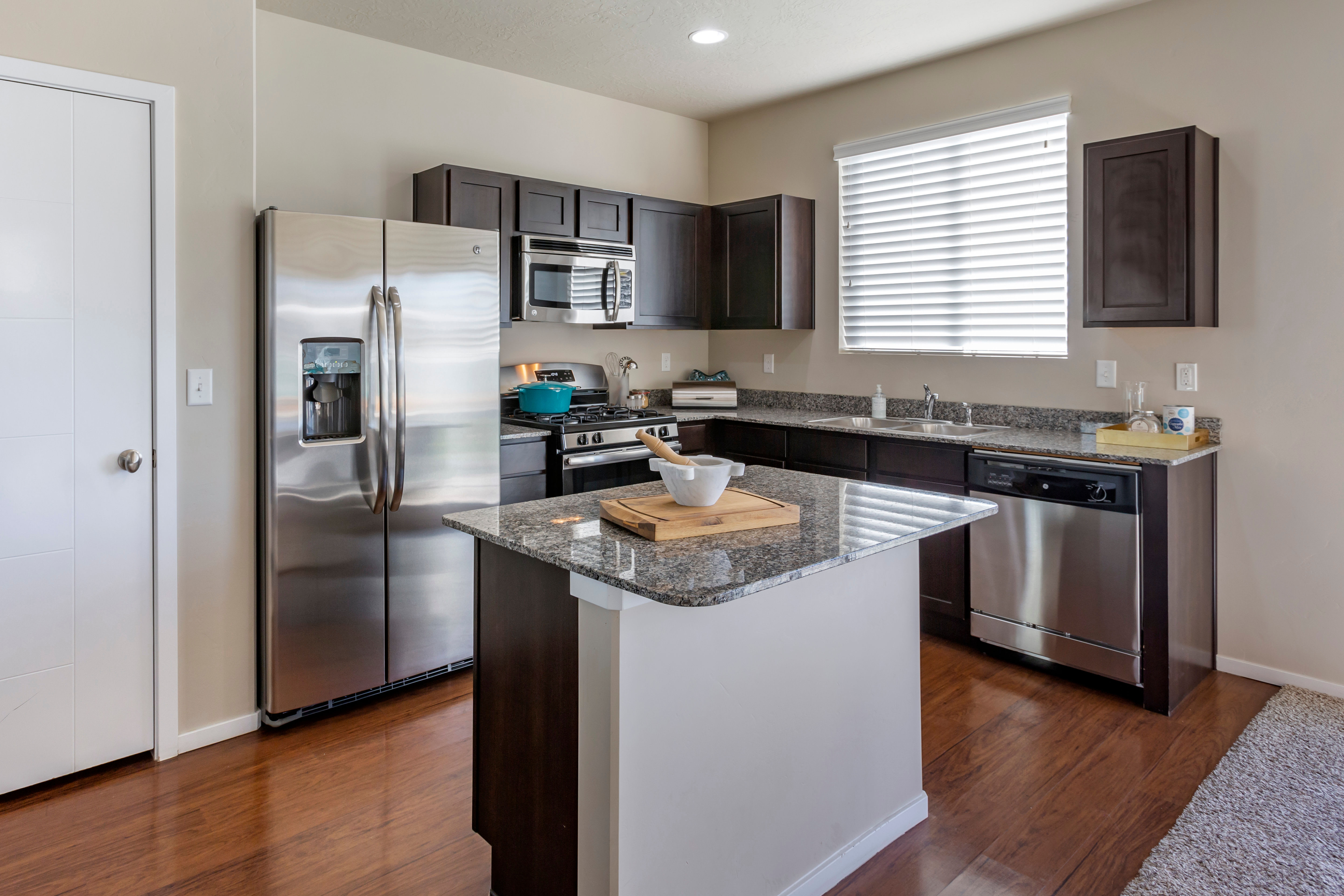 Modern kitchen with an island, granite countertops, and stainless steel appliances at Olympus at the Canyons in Herriman, Utah
