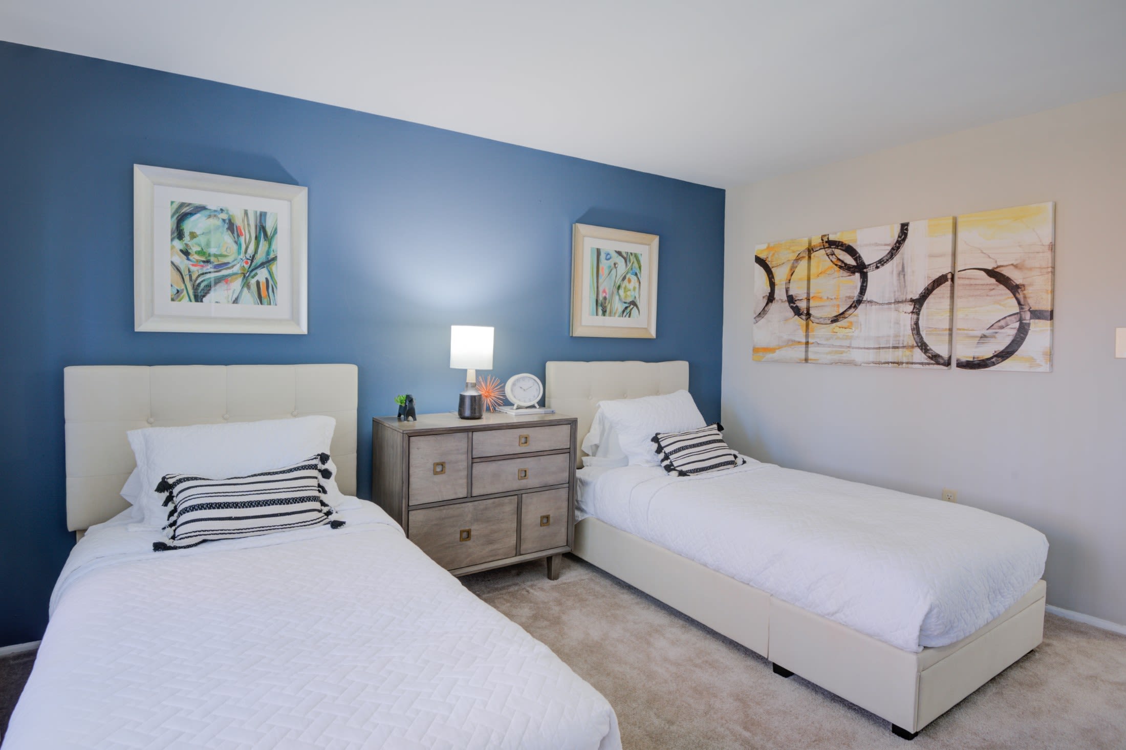 Model bedroom with twin beds and a blue accent wall at Gwynnbrook Townhomes in Baltimore, Maryland