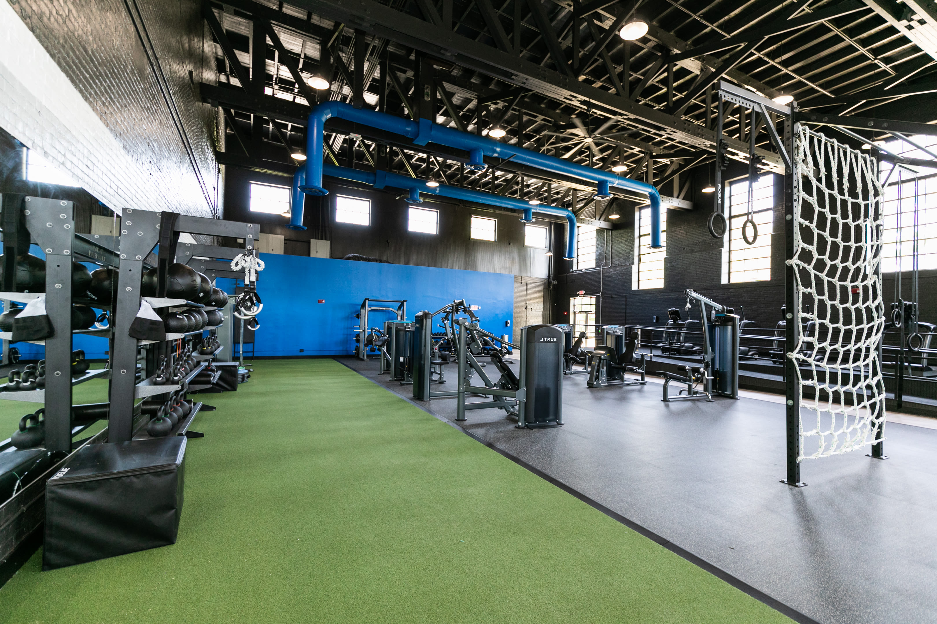 Tall ceiling and open format fitness center features treadmills, free weight, rope wall, hanging rings and more at Lofts at Riverwalk in Columbus, Georgia
