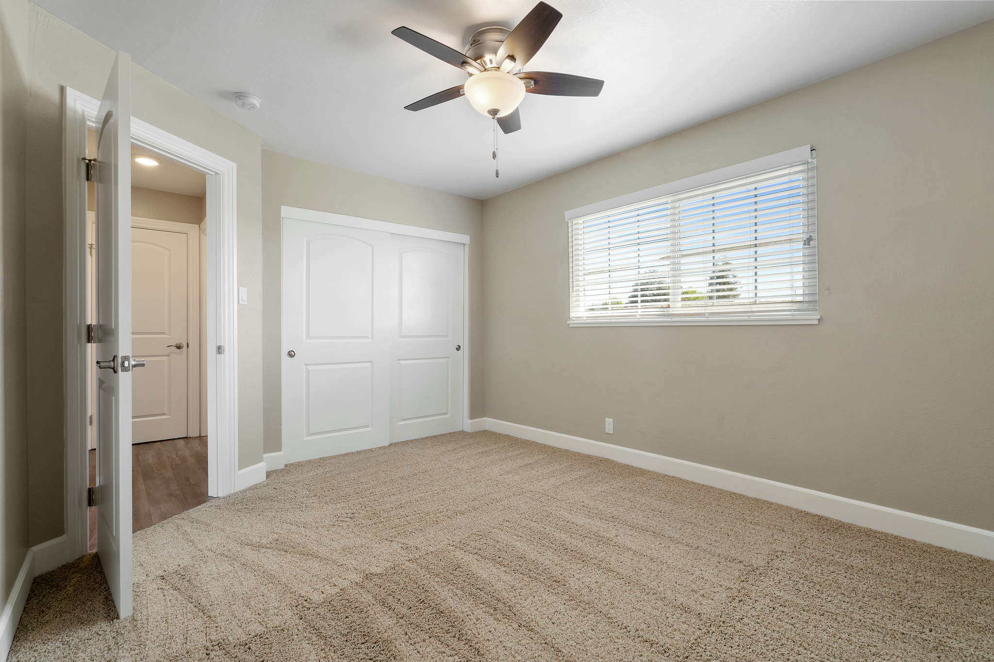 Bedroom with ceiling fan and large window at Bon Aire Apartment Homes in Castro Valley, California