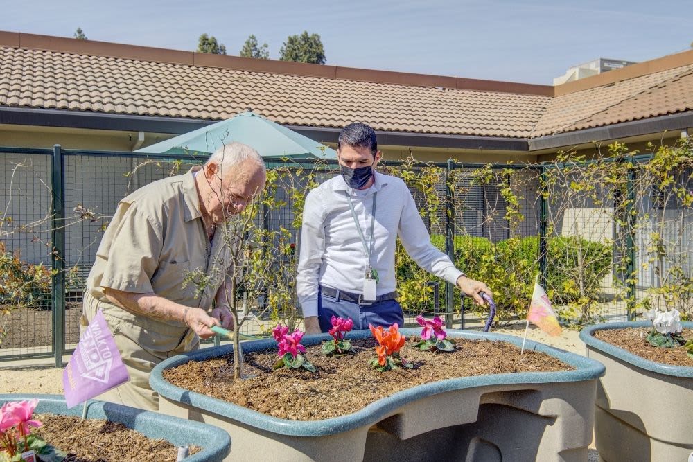 Resident and staff enjoy the memory care garden at Park Visalia in Visalia, California. 