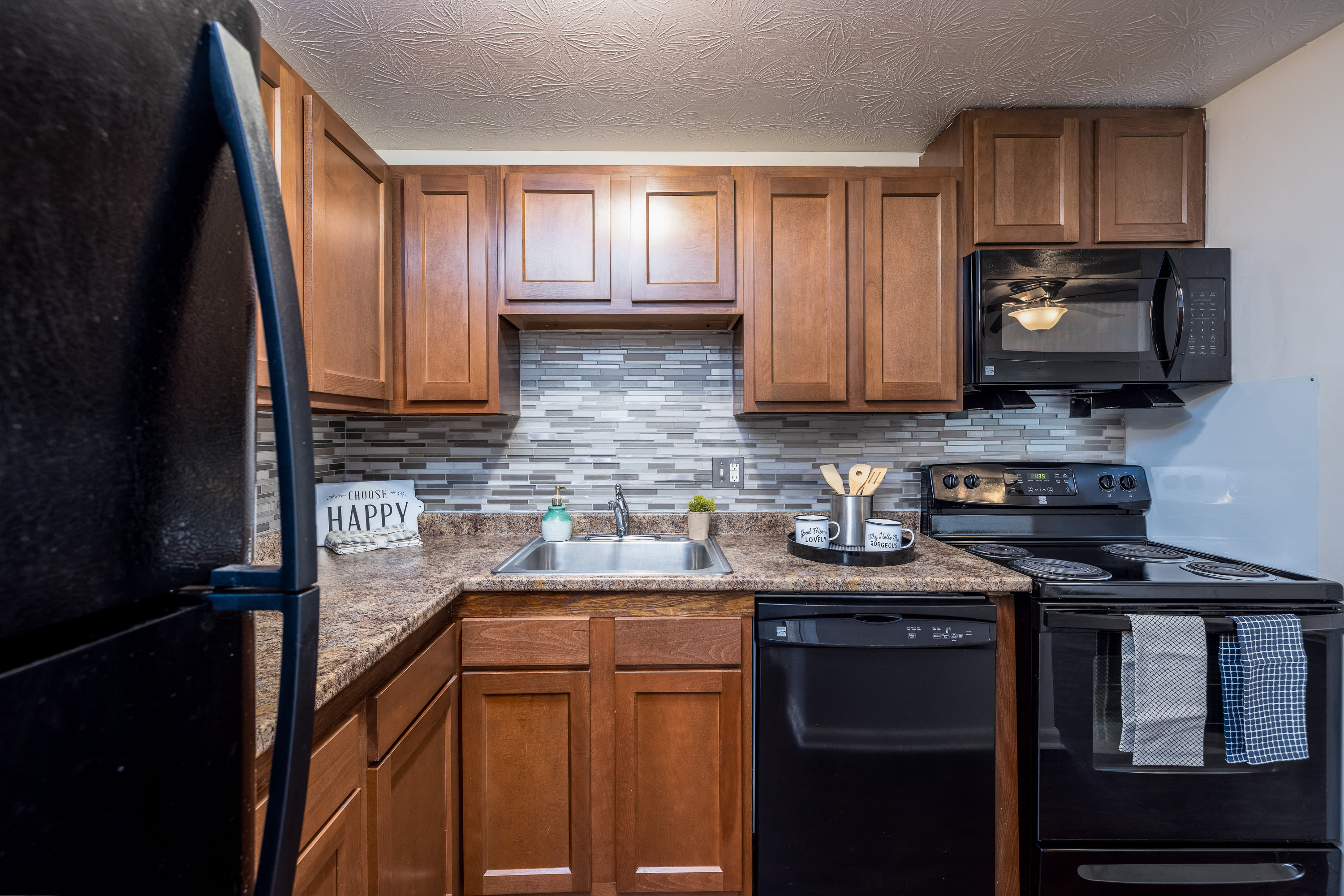 Kitchen space with black appliances at Webster Manor Apartments in Webster, New York