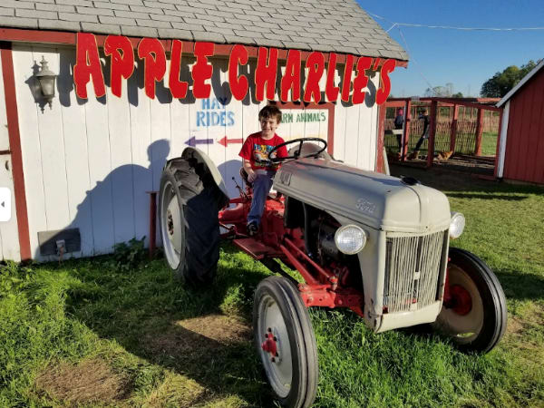 A child on a tractor in front of Apple Charlie's