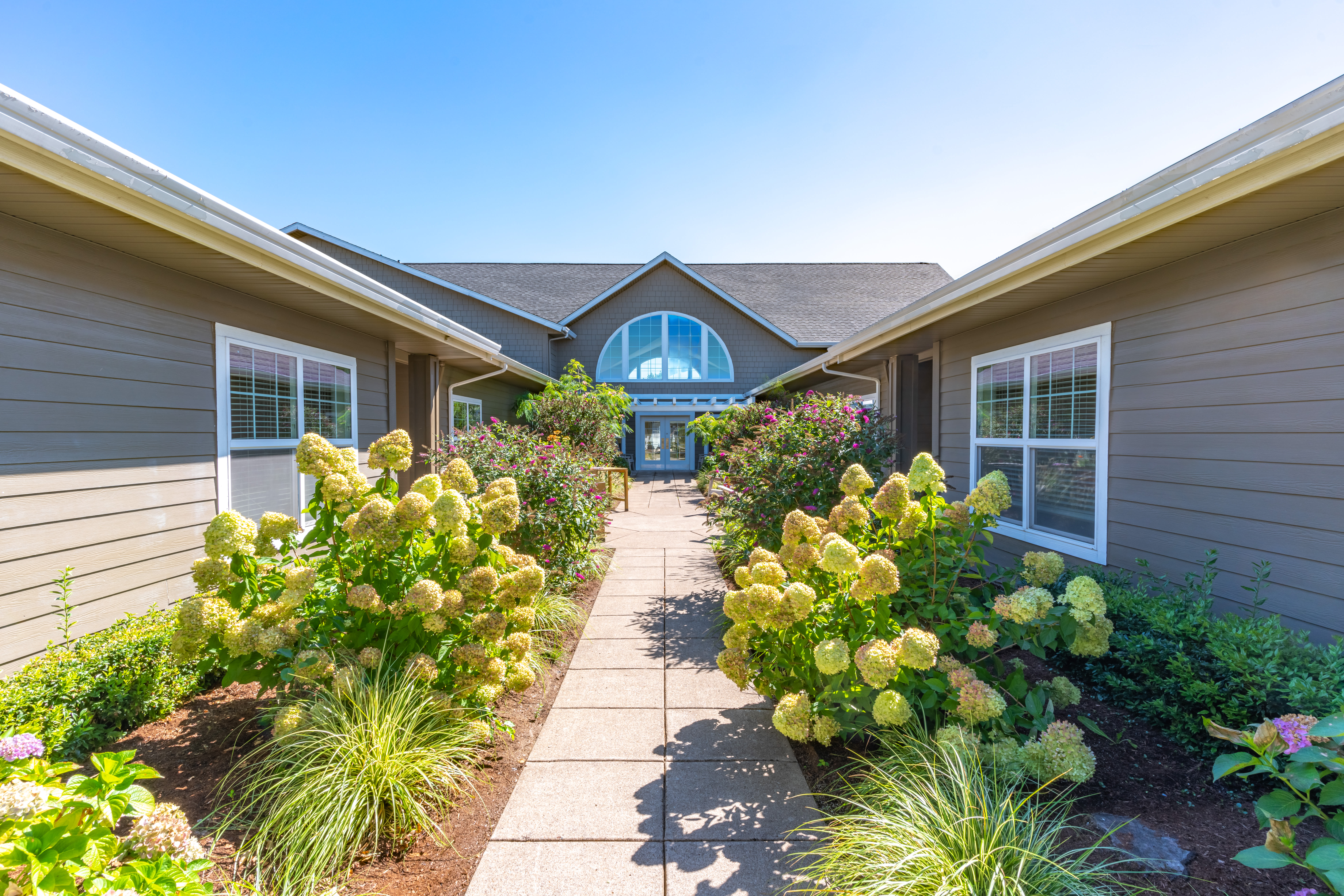 Outside walkway with beautiful greenery and landscaping at Evergreen Memory Care in Eugene, Oregon. 