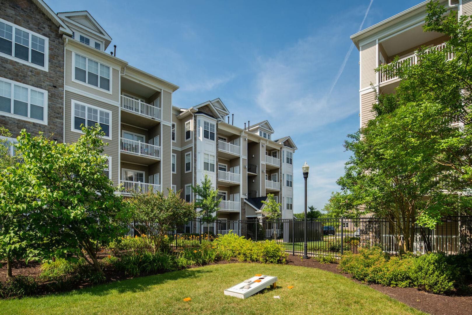 View of apartments with lots of trees and green lawn at The Elms at Stoney Run Village in Hanover, Maryland