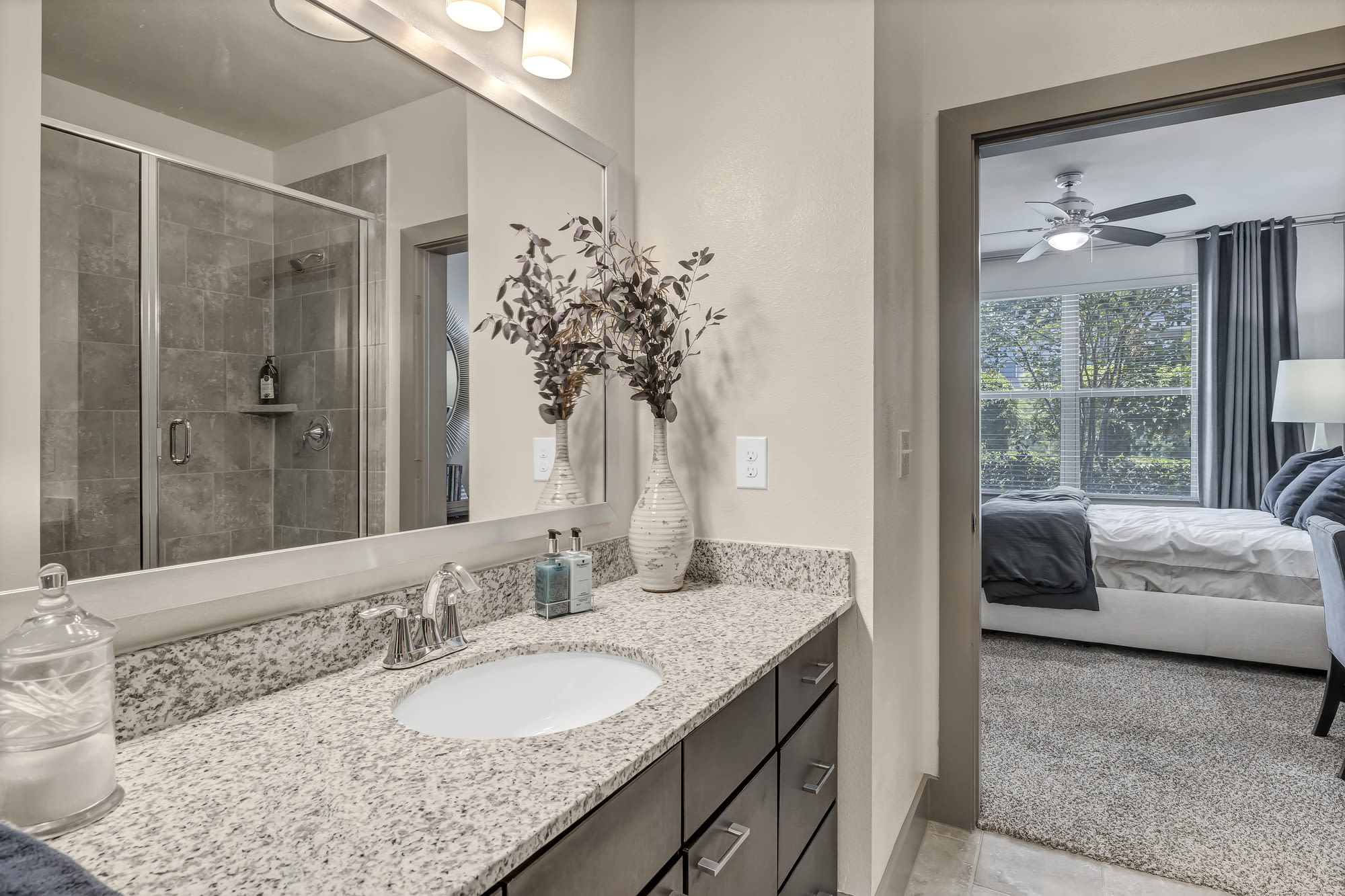 Bathroom with granite counter and tiled shower at Henley at The Rim in San Antonio, Texas