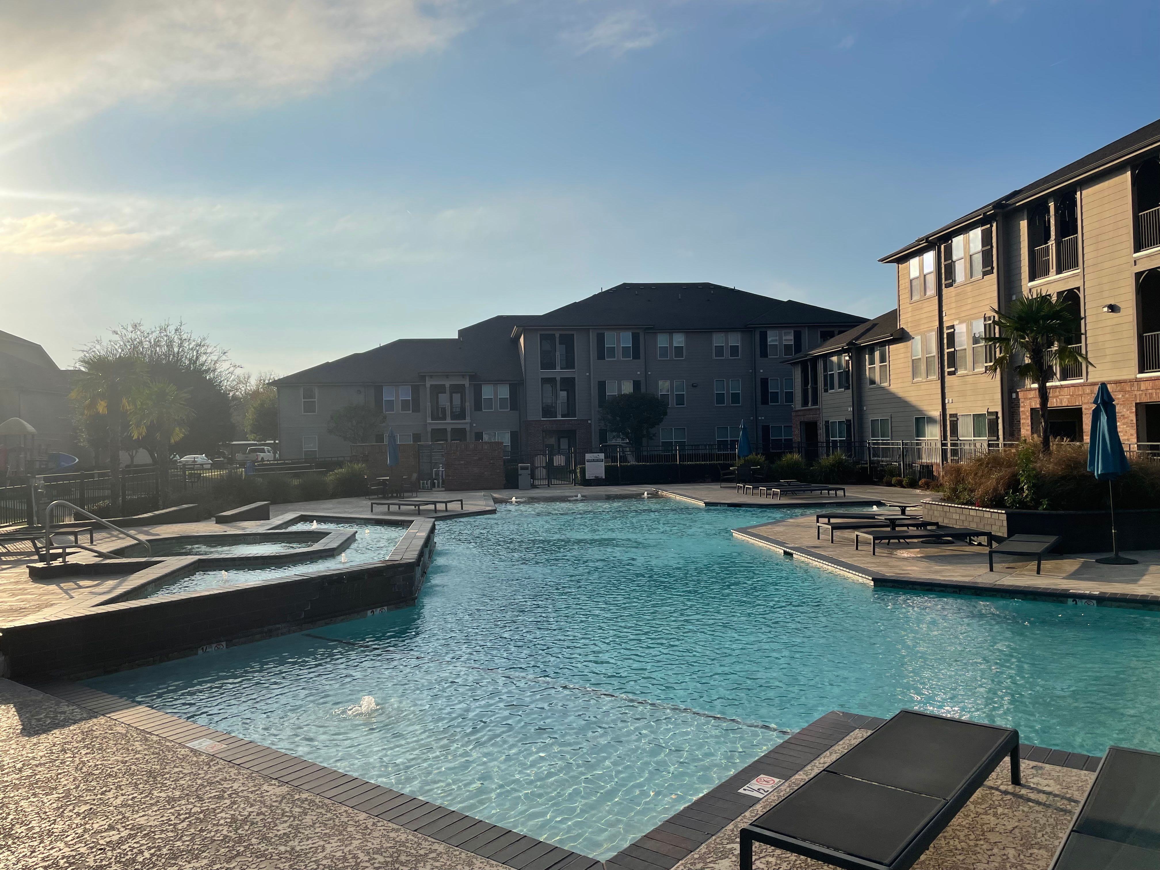 Kids putting their feet in the pool and looking at her phone at Le Rivage Luxury Apartments in Bossier City, Louisiana