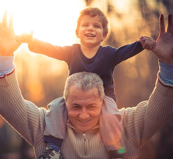 One of our active residents giving his grandson a piggy-back ride at Churchill Place Memory Care in Glen Ellyn, Illinois