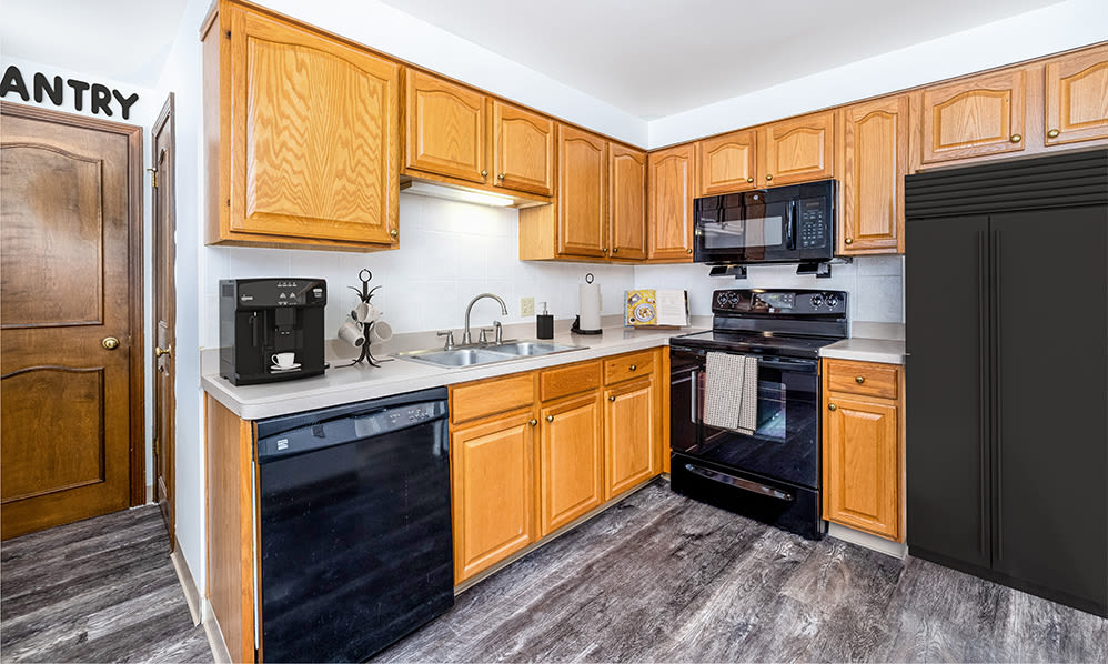 Large kitchen with oak cabinets and black appliances at Green Lake Apartments & Townhomes in Orchard Park, New York